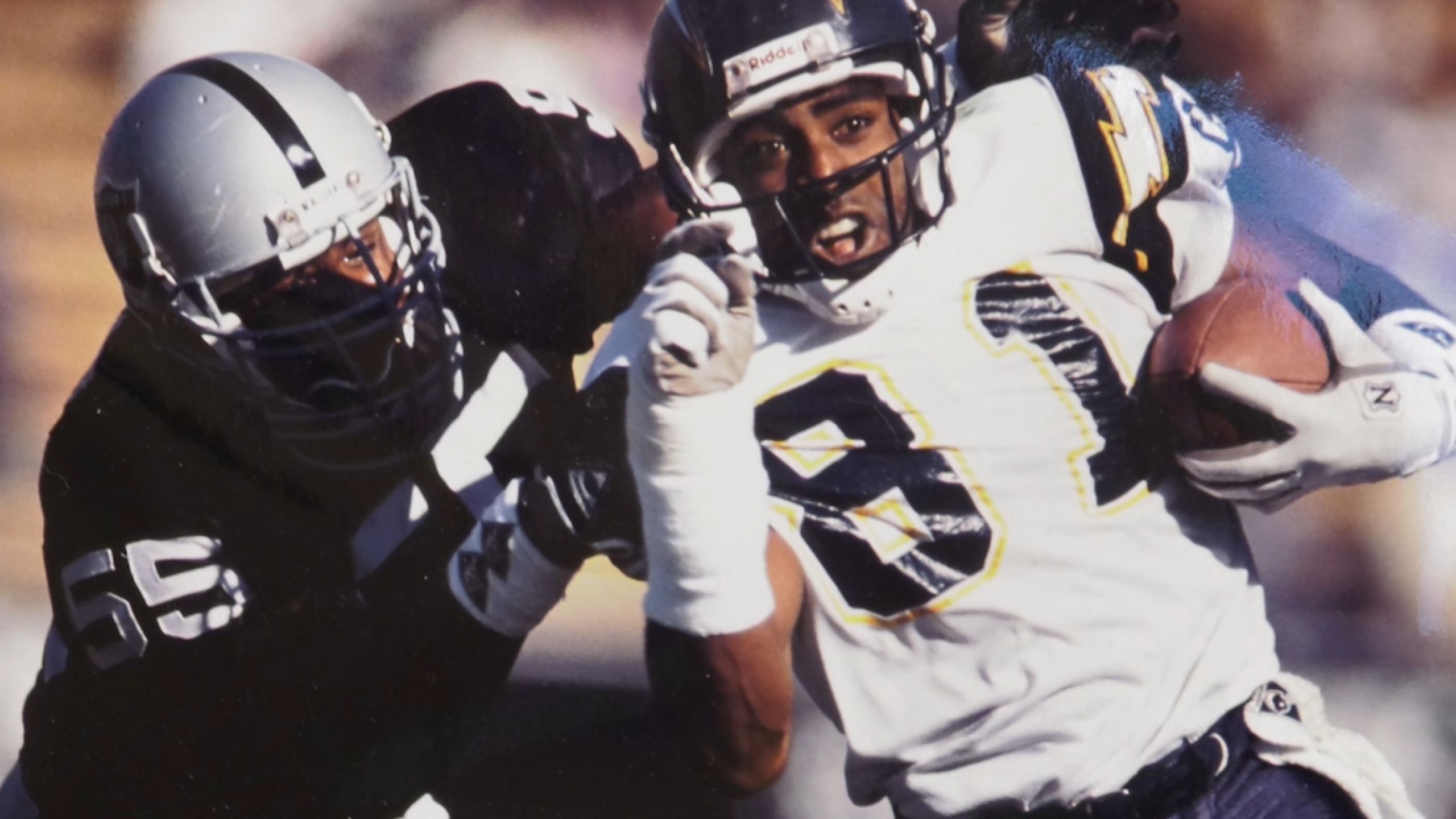 Nate Lewis during his NFL days being tackled as he runs down a field with the football.