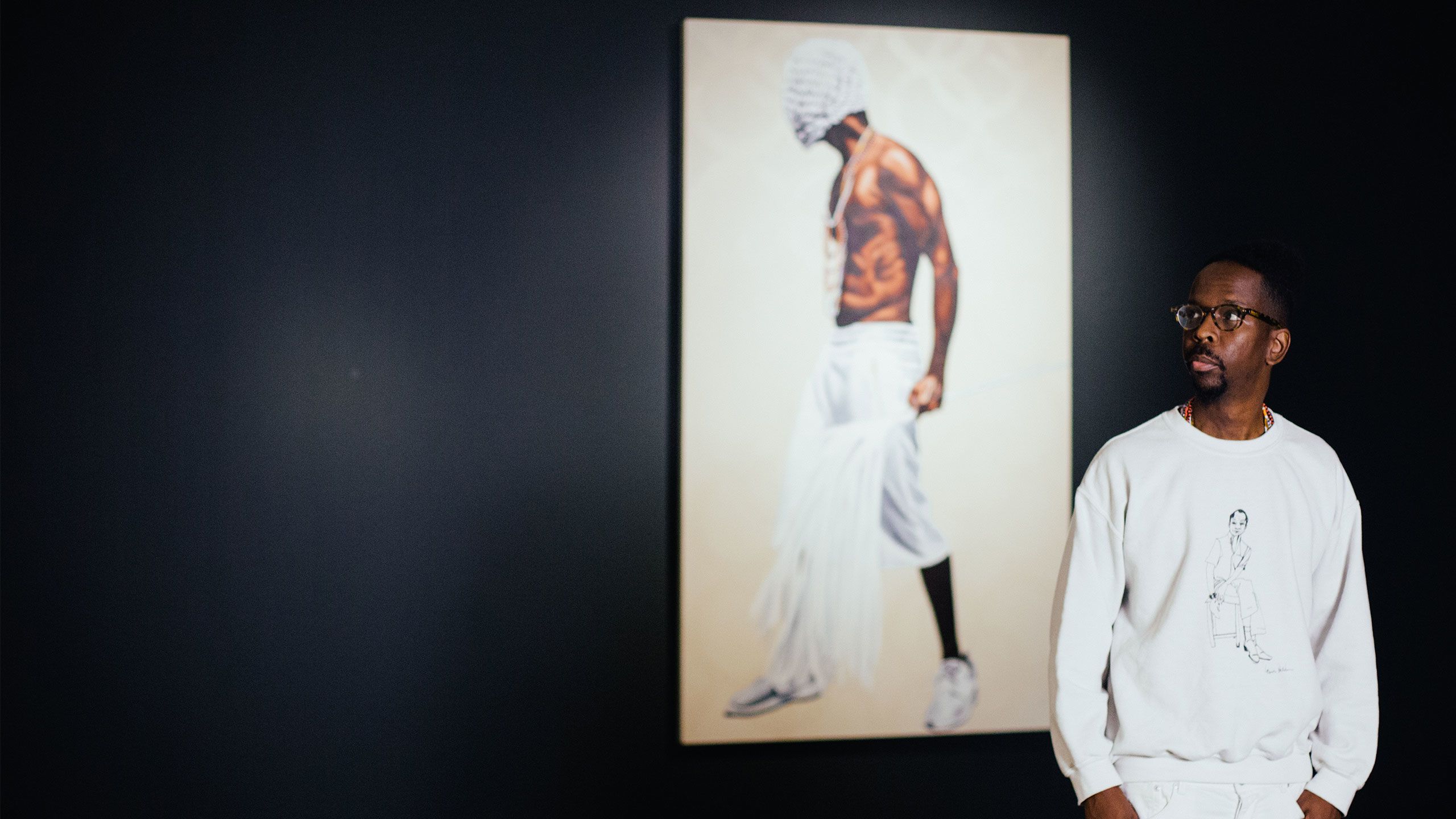 Fahamu Pecou stands in front of a wall displaying his art