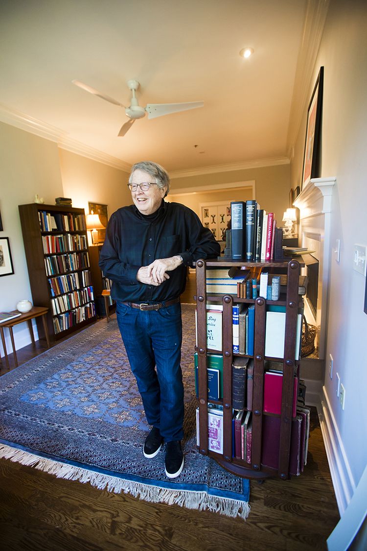 Burkett leaning on a turning bookcase in his home library
