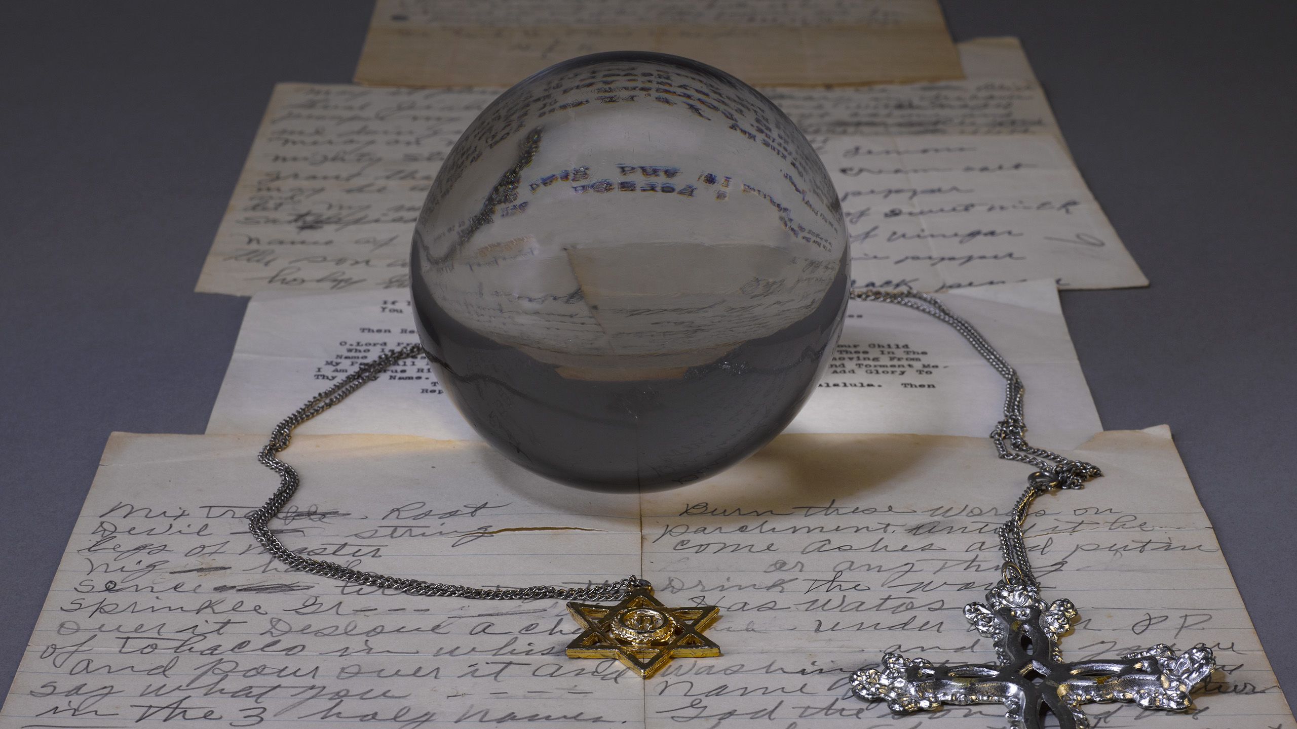 A crystal ball sitting on top of pages of spells
