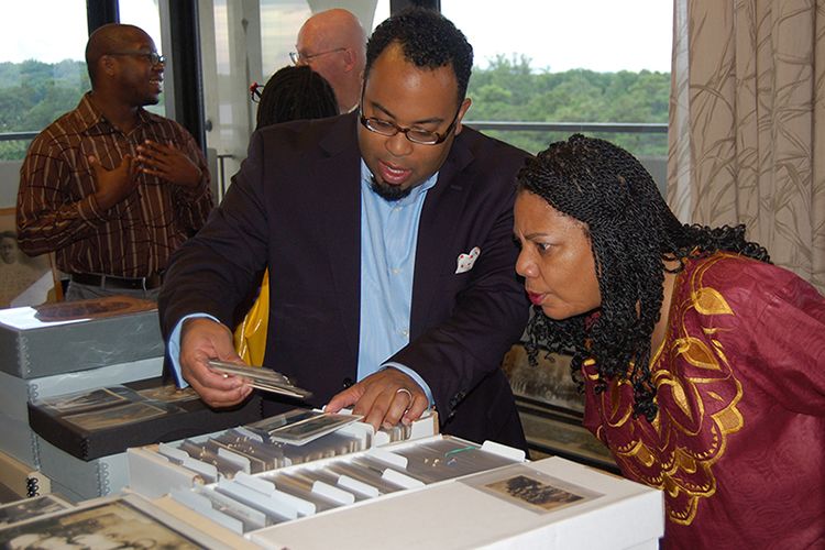 Kevin Young holding out a photograph as Kimberly Wallace-Sanders studies it