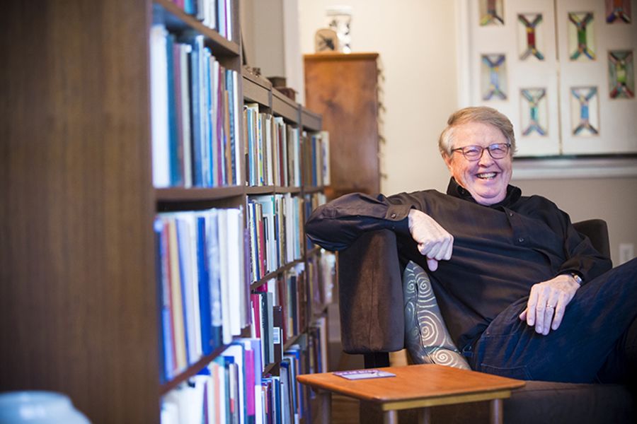 Burkett smiling and sitting in a chair in his home library