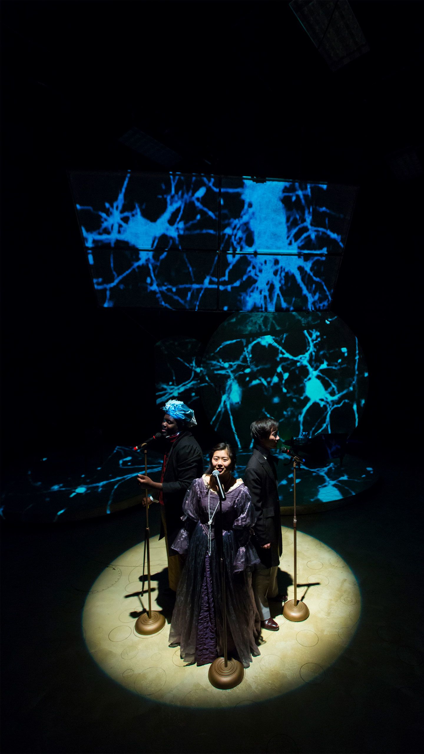 An actress stands in front of a blue patterned backdrop performing in "Ada and the Engine."