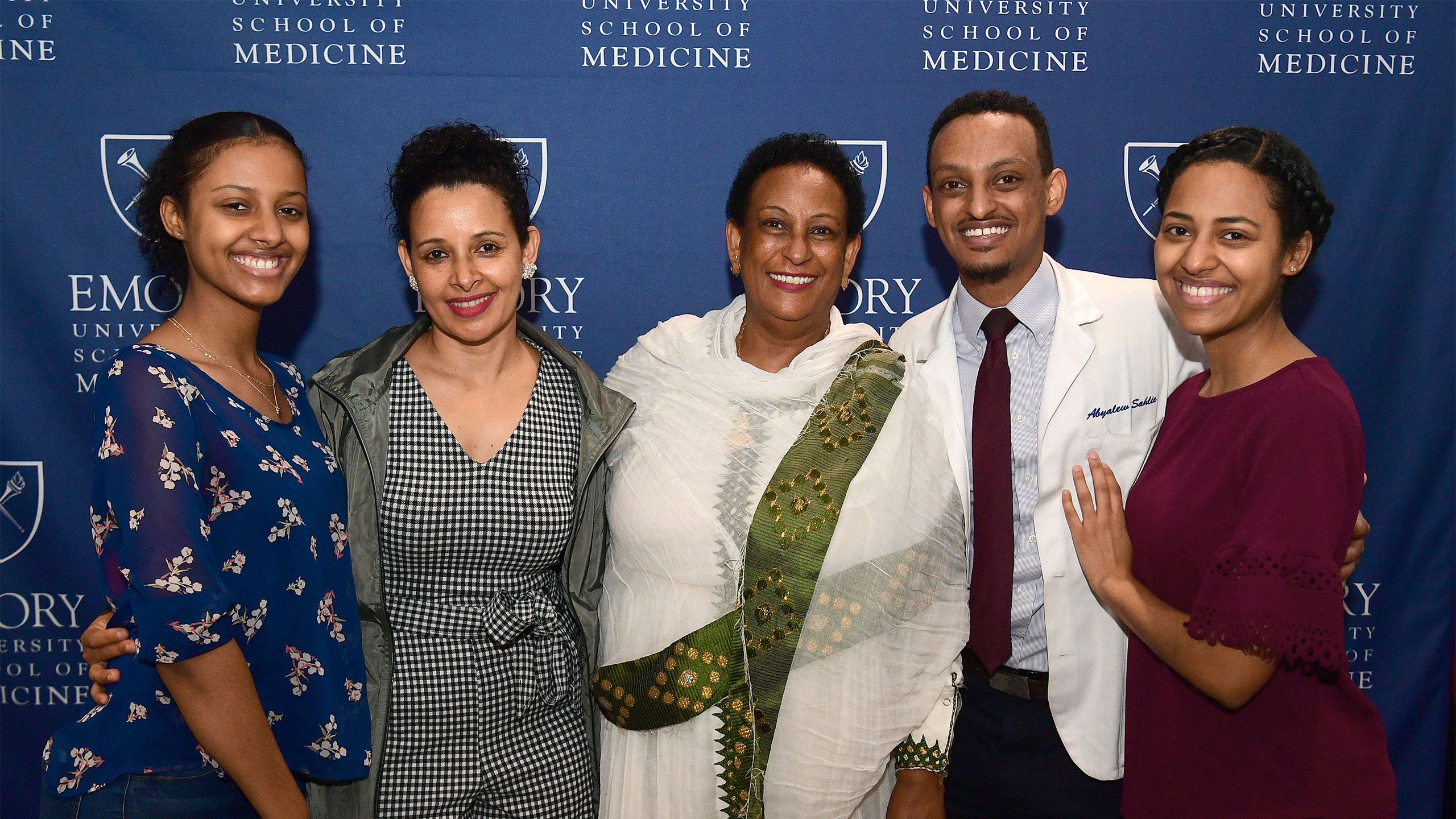 A student poses with family members in front of an Emory Medicine banner on Match Day.