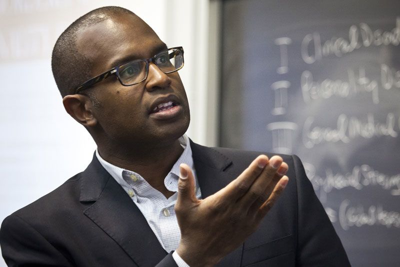 Oxford professor Ken Carter talks in front of a chalkboard.