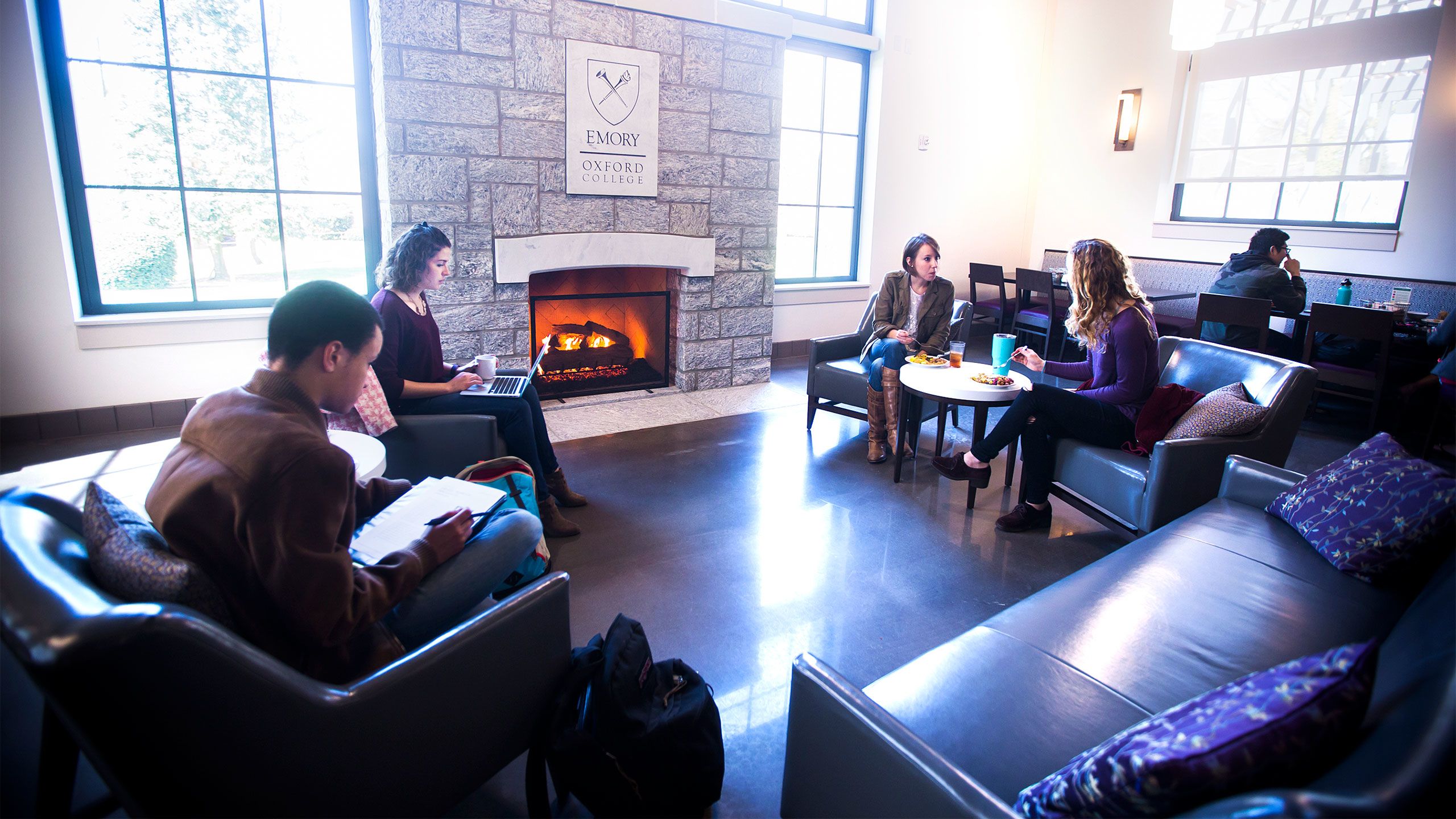 Students sit and talk on couches surrounding a fireplace in the Oxford dining hall.