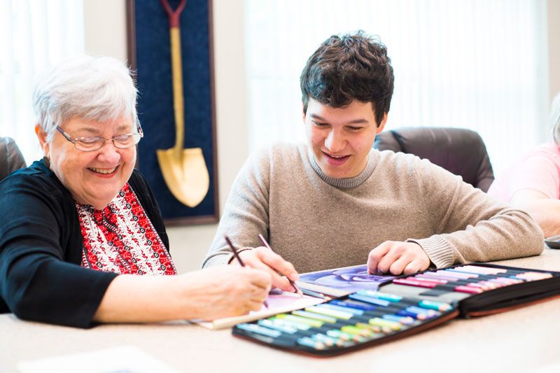 A student draws with an older woman at the senior center.