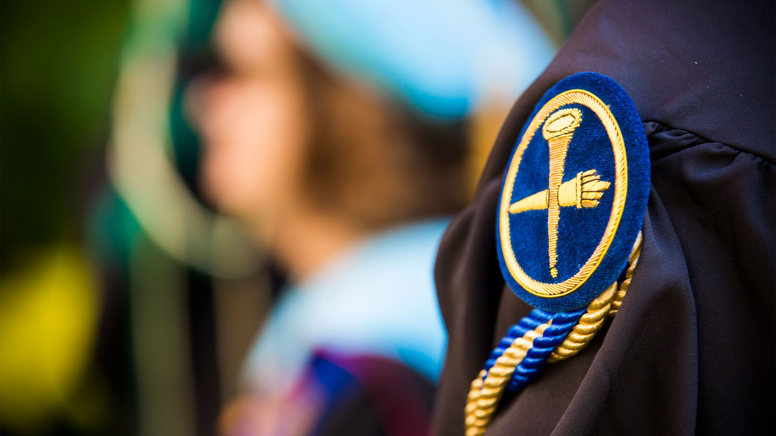 Students in caps and gowns sit in rows at Commencement