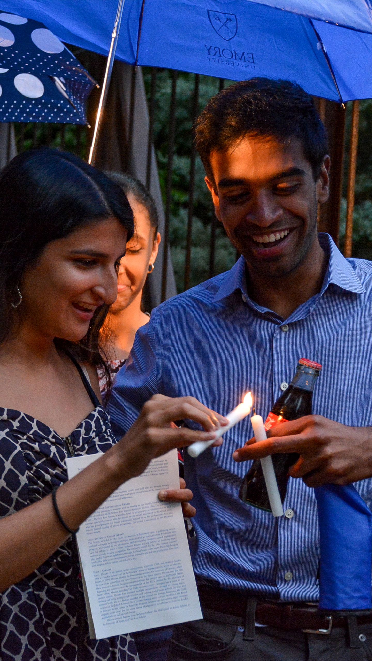 Students holding umbrellas and candles