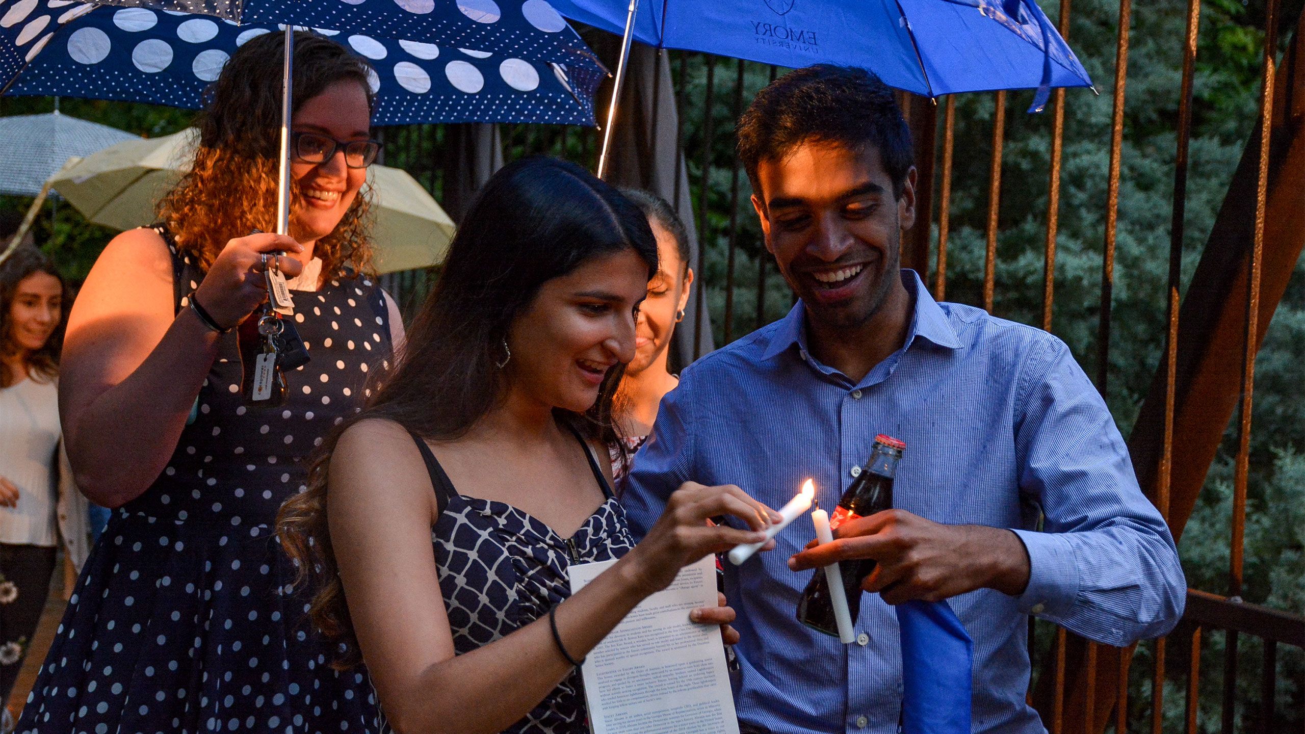 Students holding umbrellas and candles