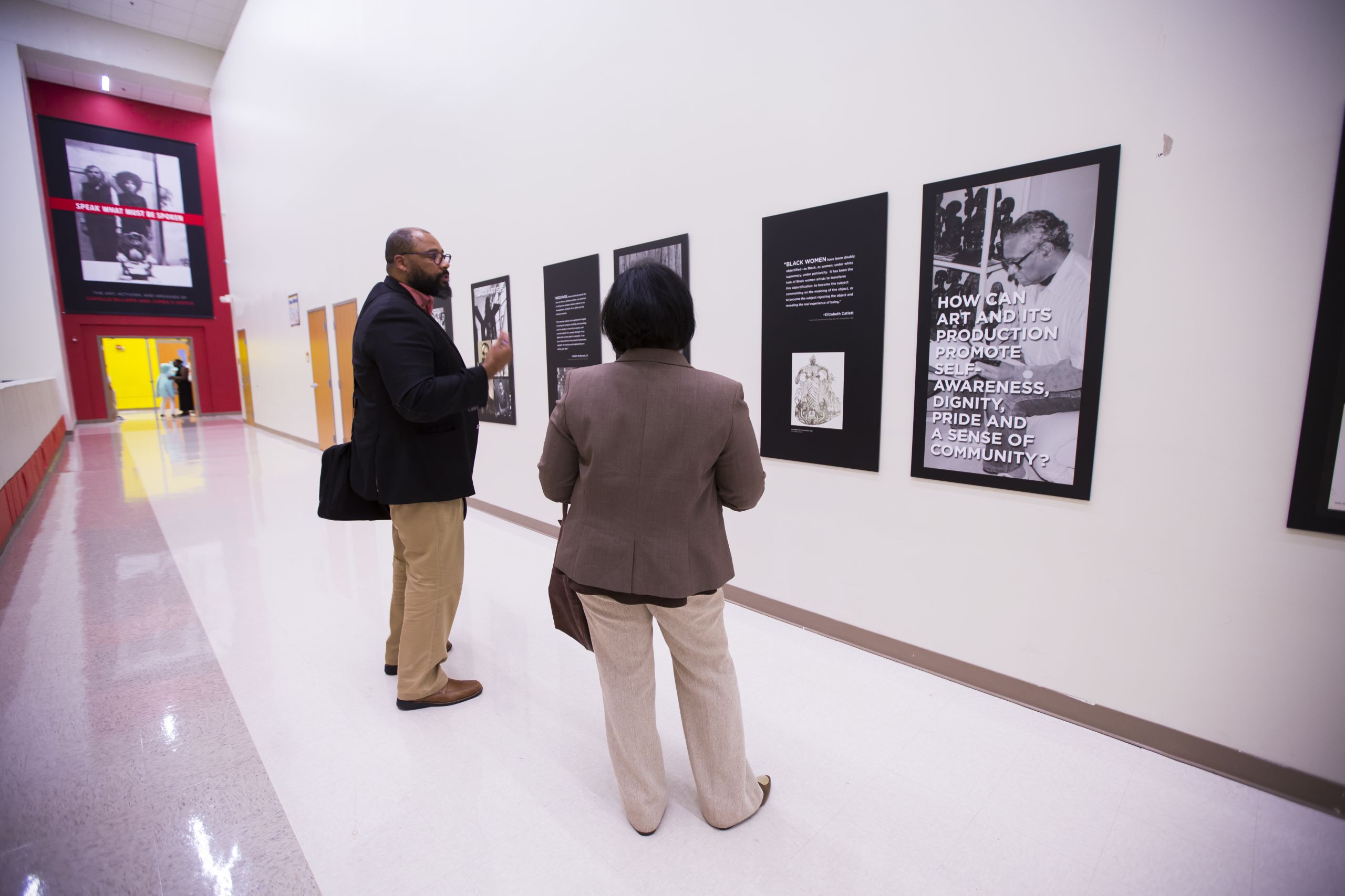 Pellom McDaniels is seen from behind as he faces a display of exhibit posters lining a middle school hallway.