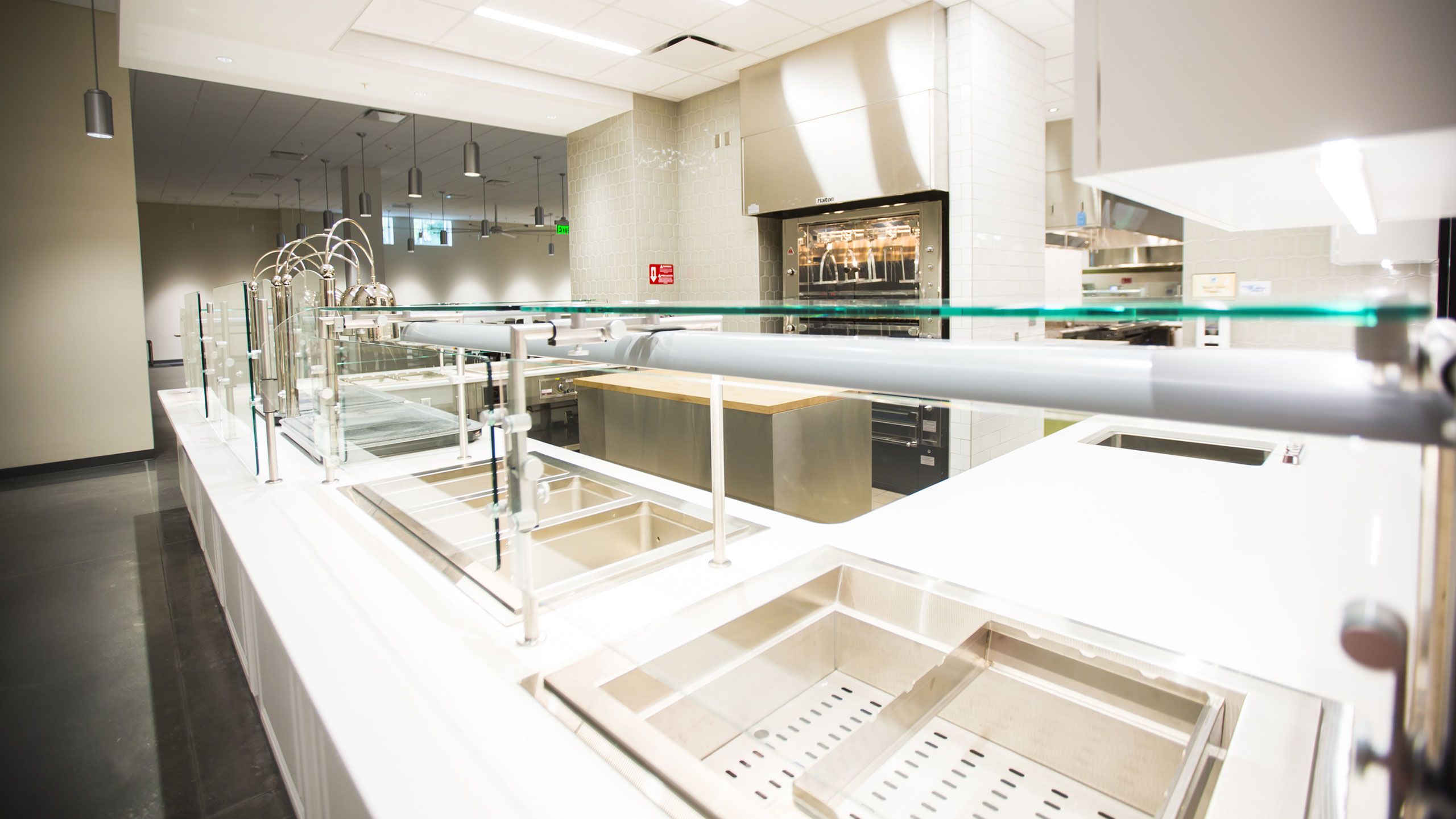 Several sections for housing food ready to serve sits behind glass panels. A rotisserie and carving station is behind the serving stations