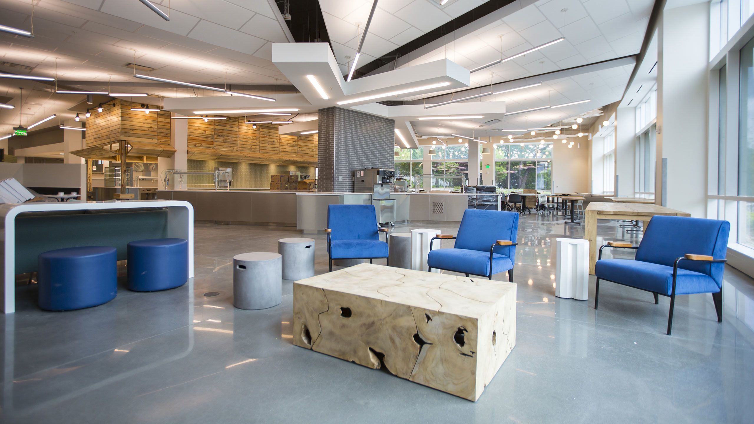 Blue armchairs and a rustic-style coffee table open to a kitchen area