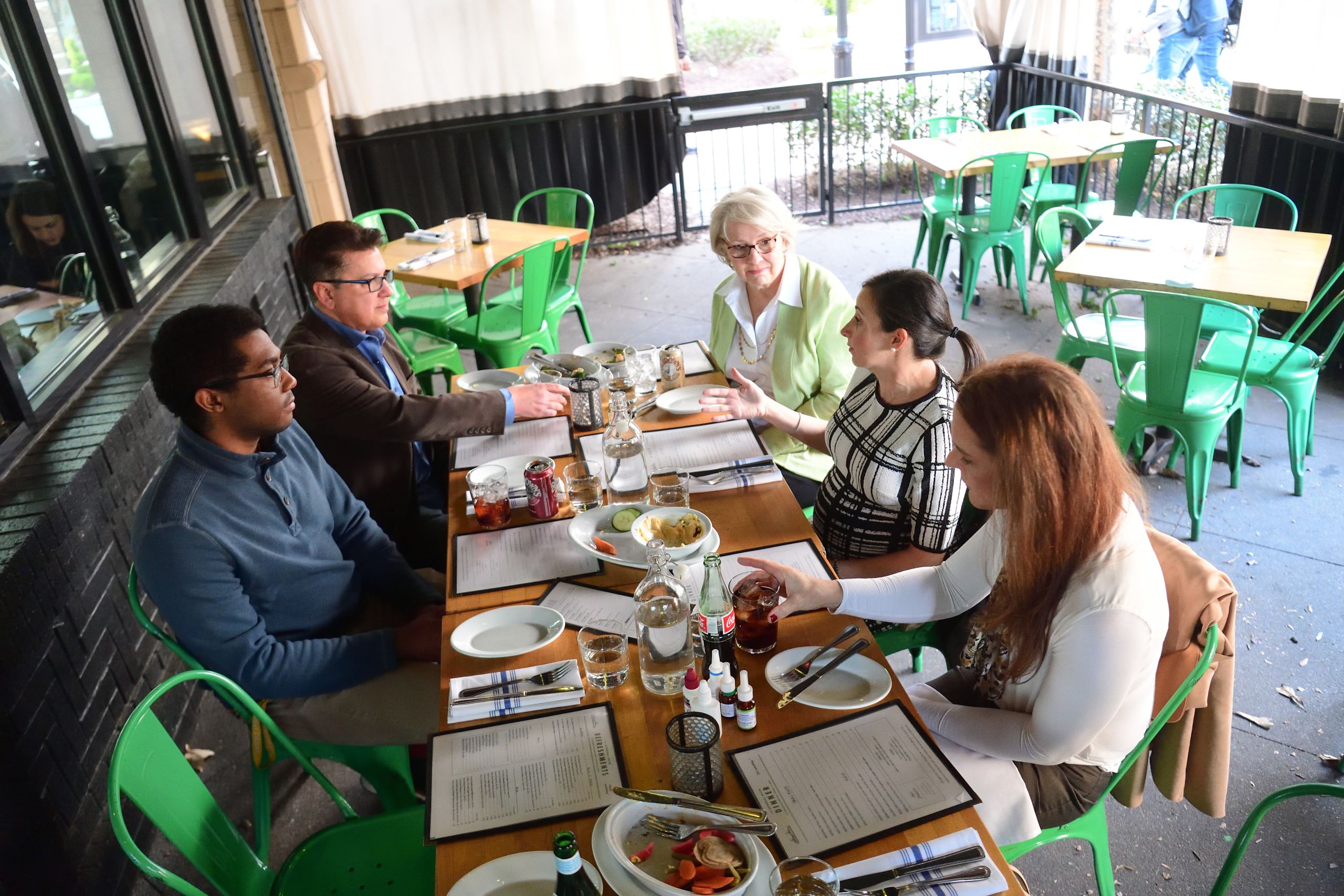 A group of four panelists and Dr. Marissa Shams on a long table on the patio of General Muir restaurant. 
