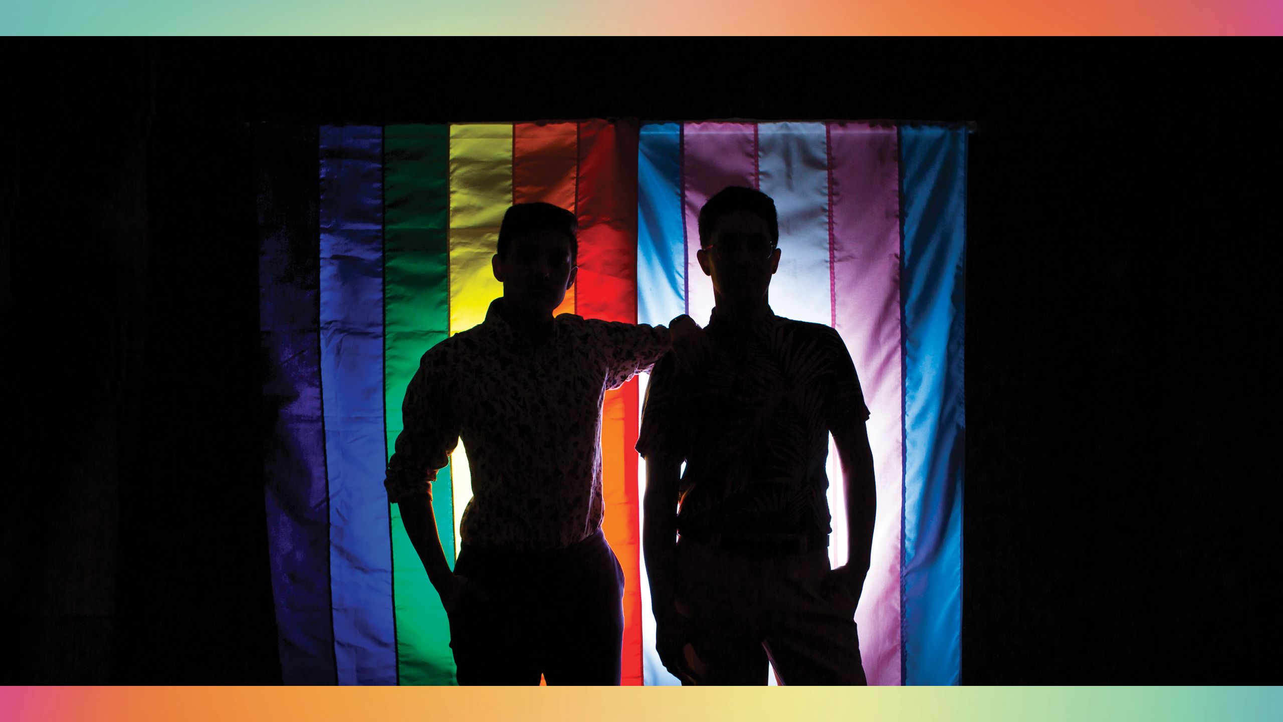 Silhouette of students standing in front of pride flag