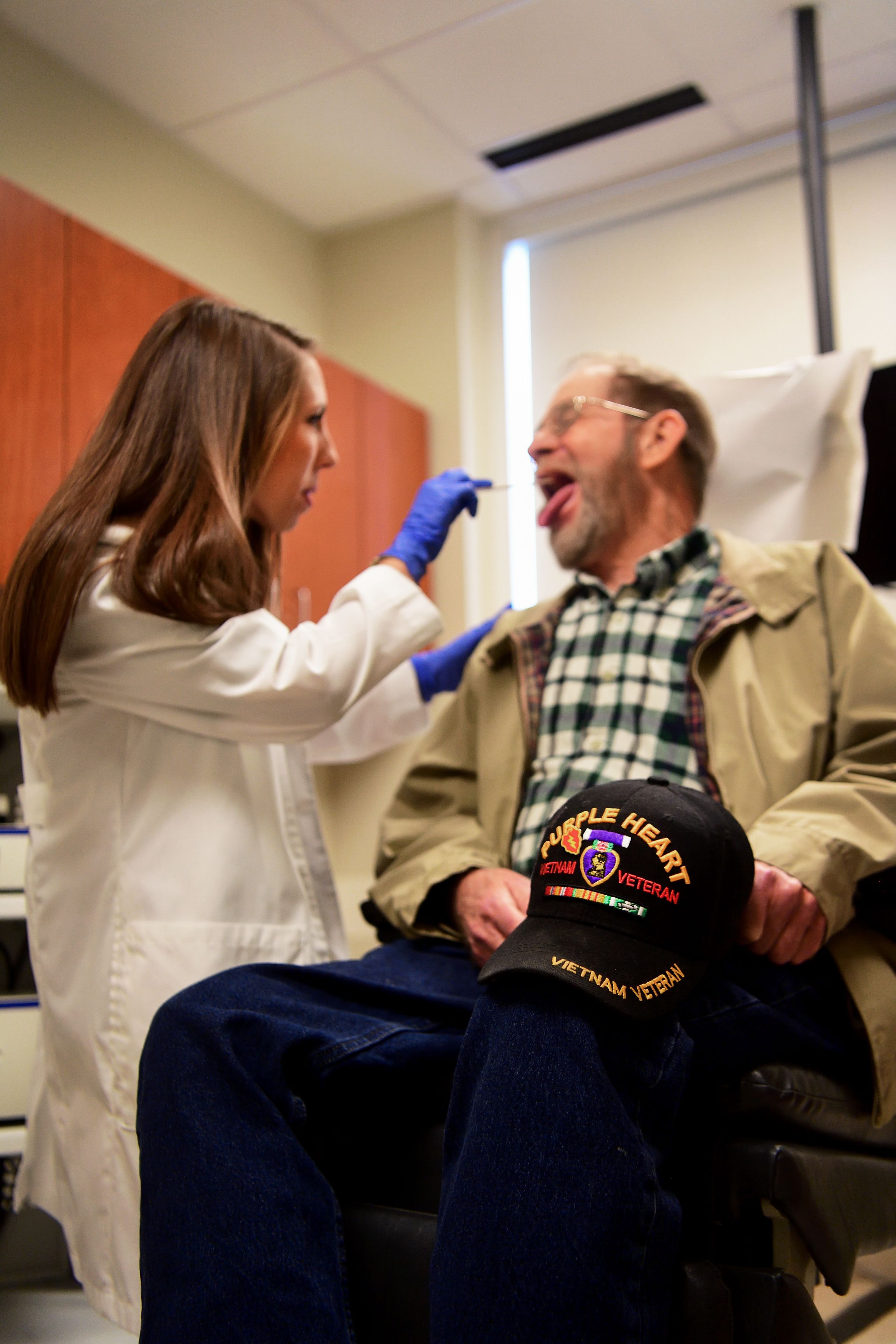 A speech and swallowing therapist uses a tongue depressor to look at a patient's throat and check for any obstructions. 