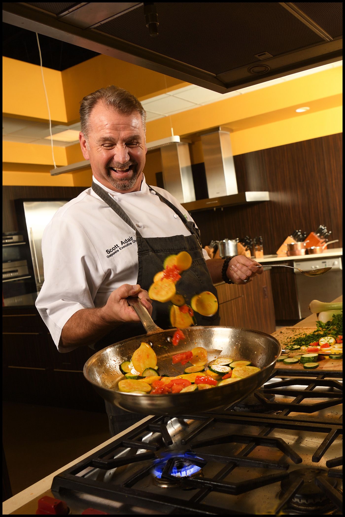 Chef Scott Adair shows off his cooking skills by flipping a medley of mixed vegetables out of the pan.   