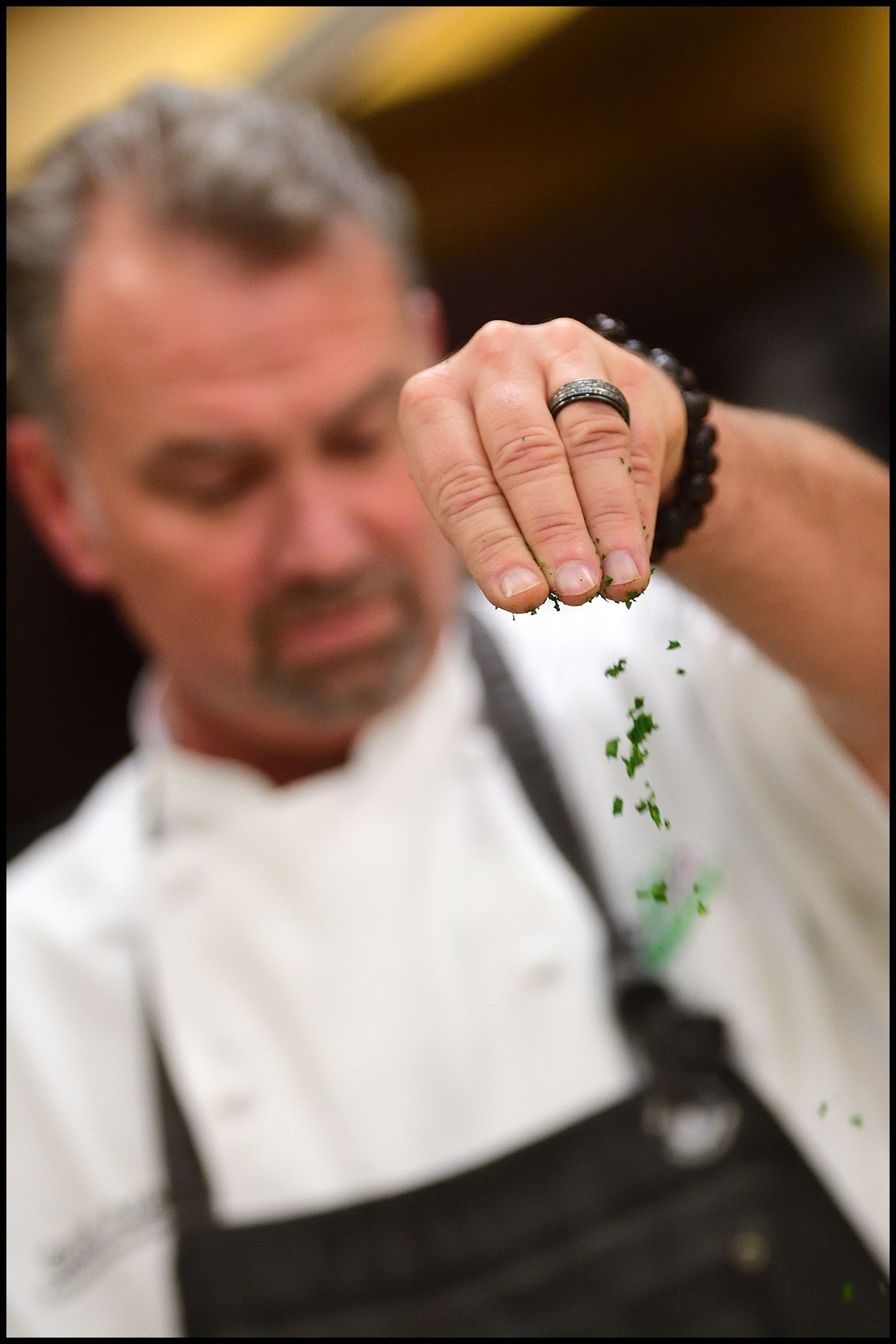 A chef who was treated for tongue cancer is seen sprinkling chopped parsley.