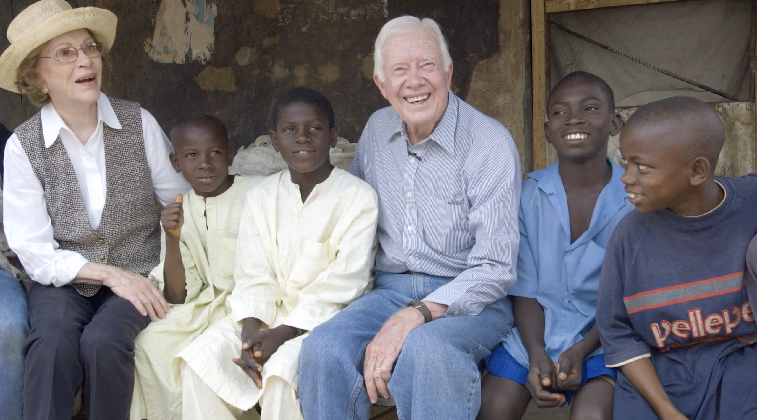 Former President Carter and Rosalynn Carter sit with a group of young African boys