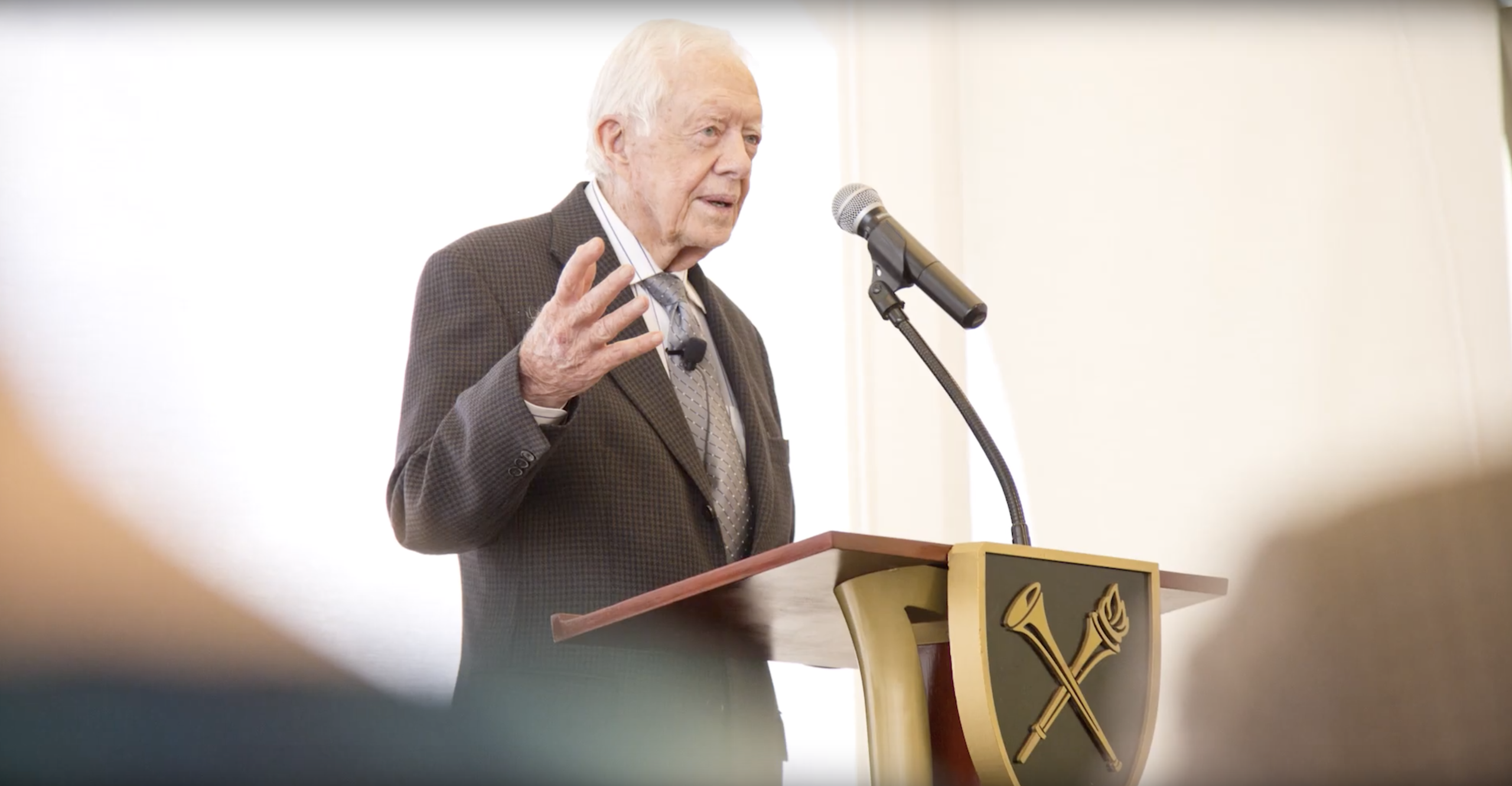 President Carter speaks to a crowd while standing at a podium