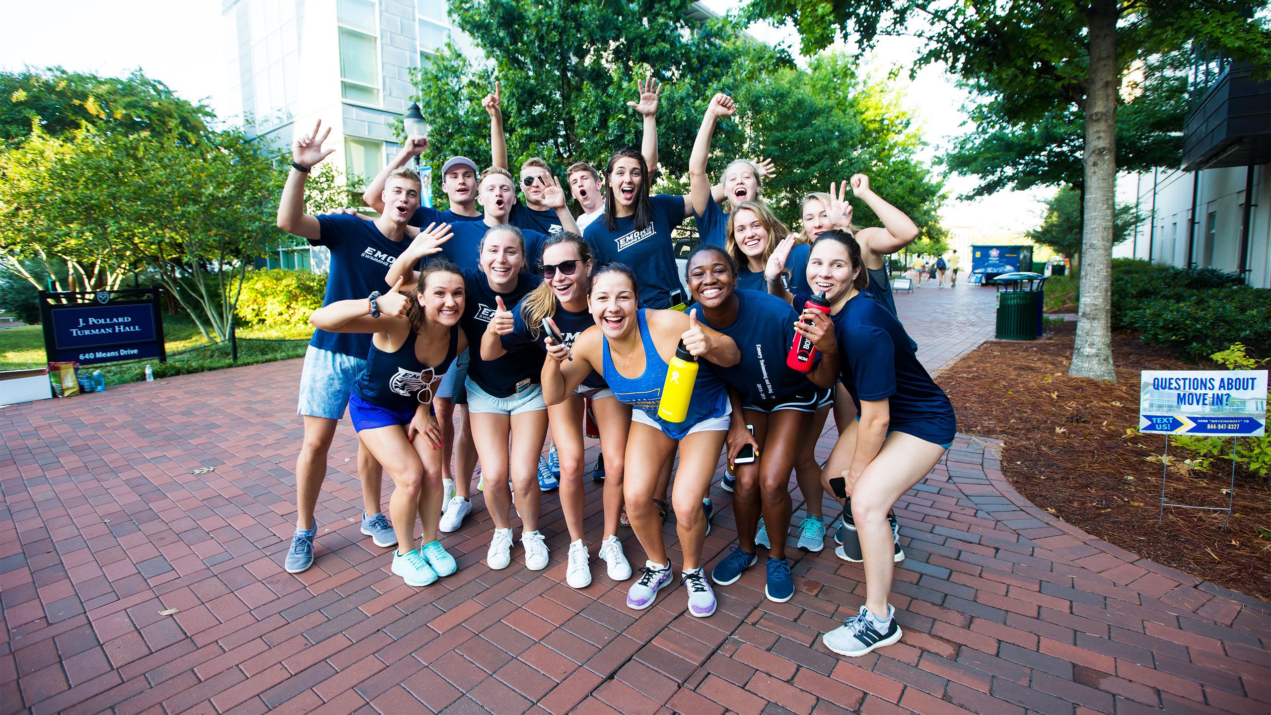 Students in blue Emory t-shirts cheer to welcome new students