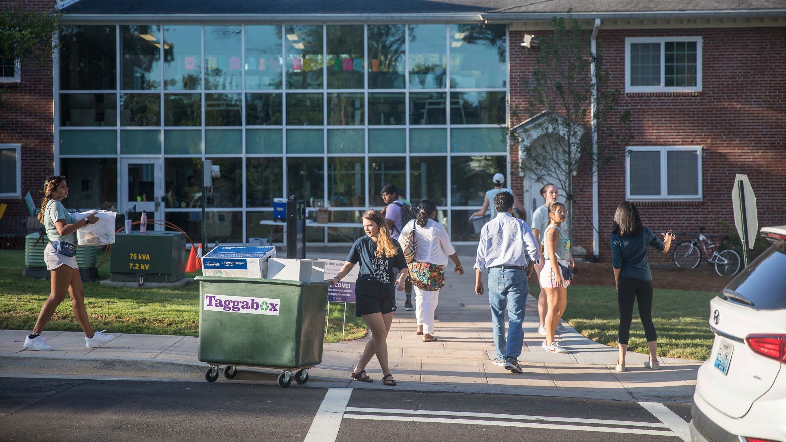 Students carry luggage in front of an Oxford residence hall