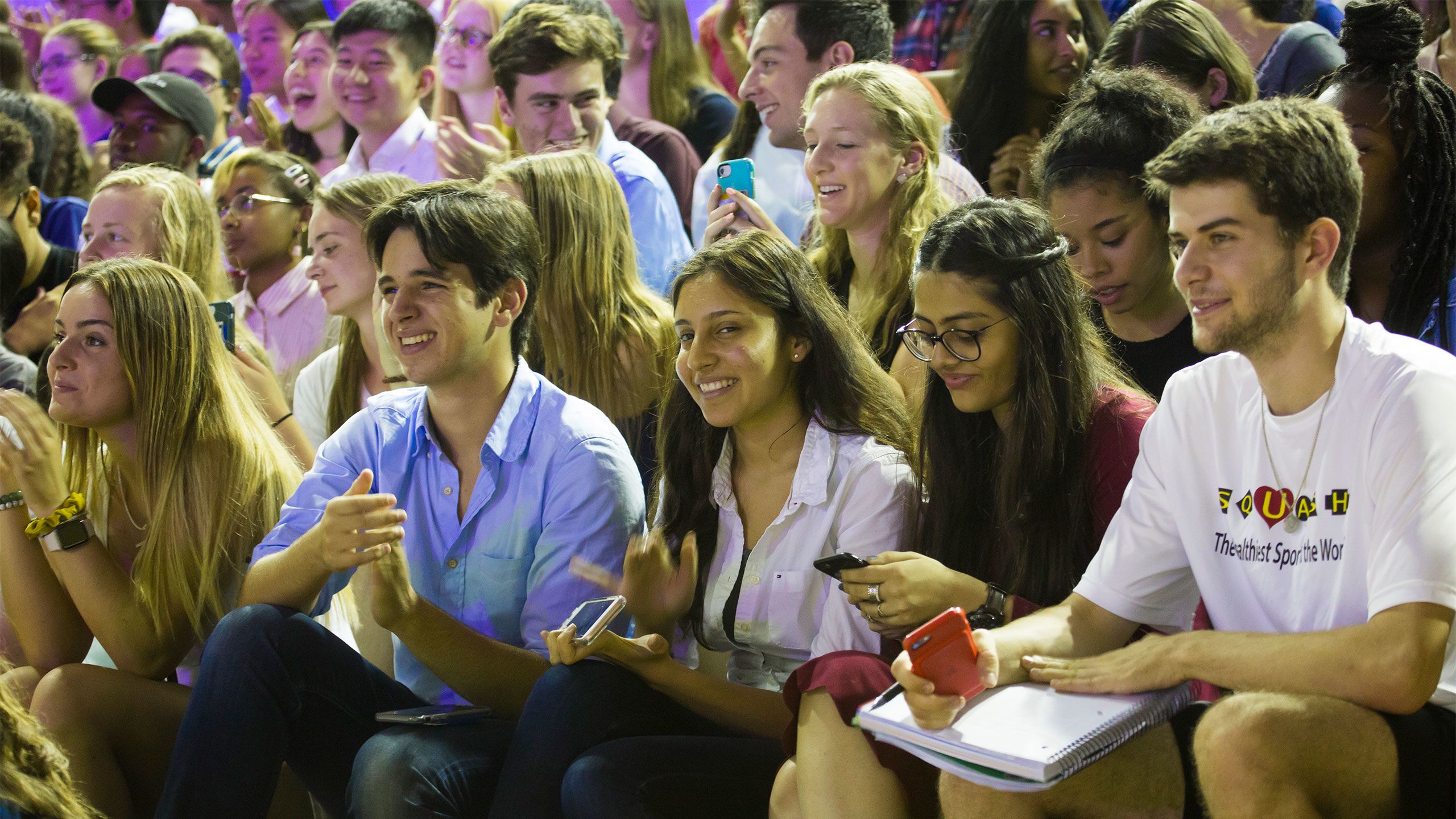 smiling students clap as they look toward the stage