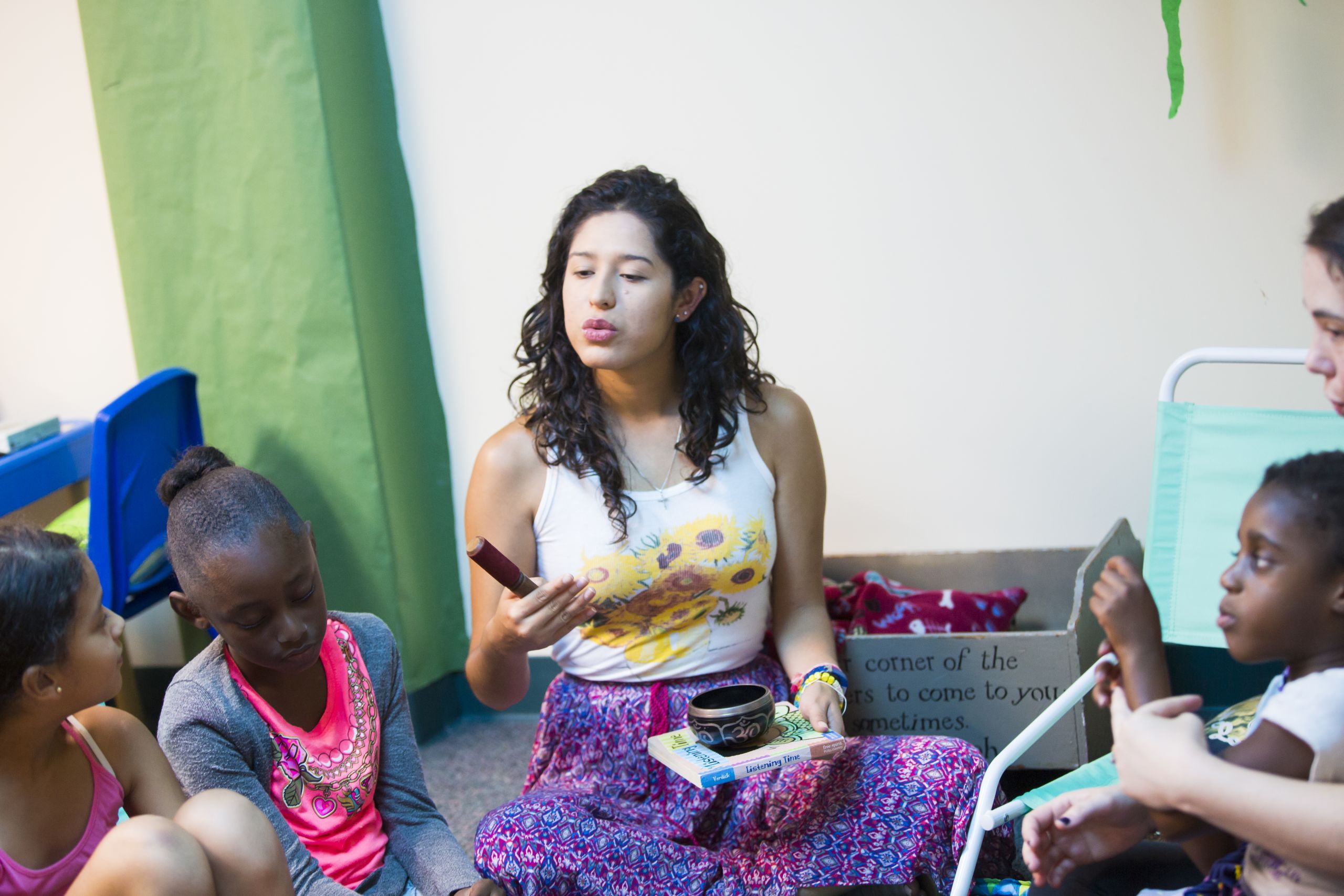 College student sits on floor with children during quiet activity time