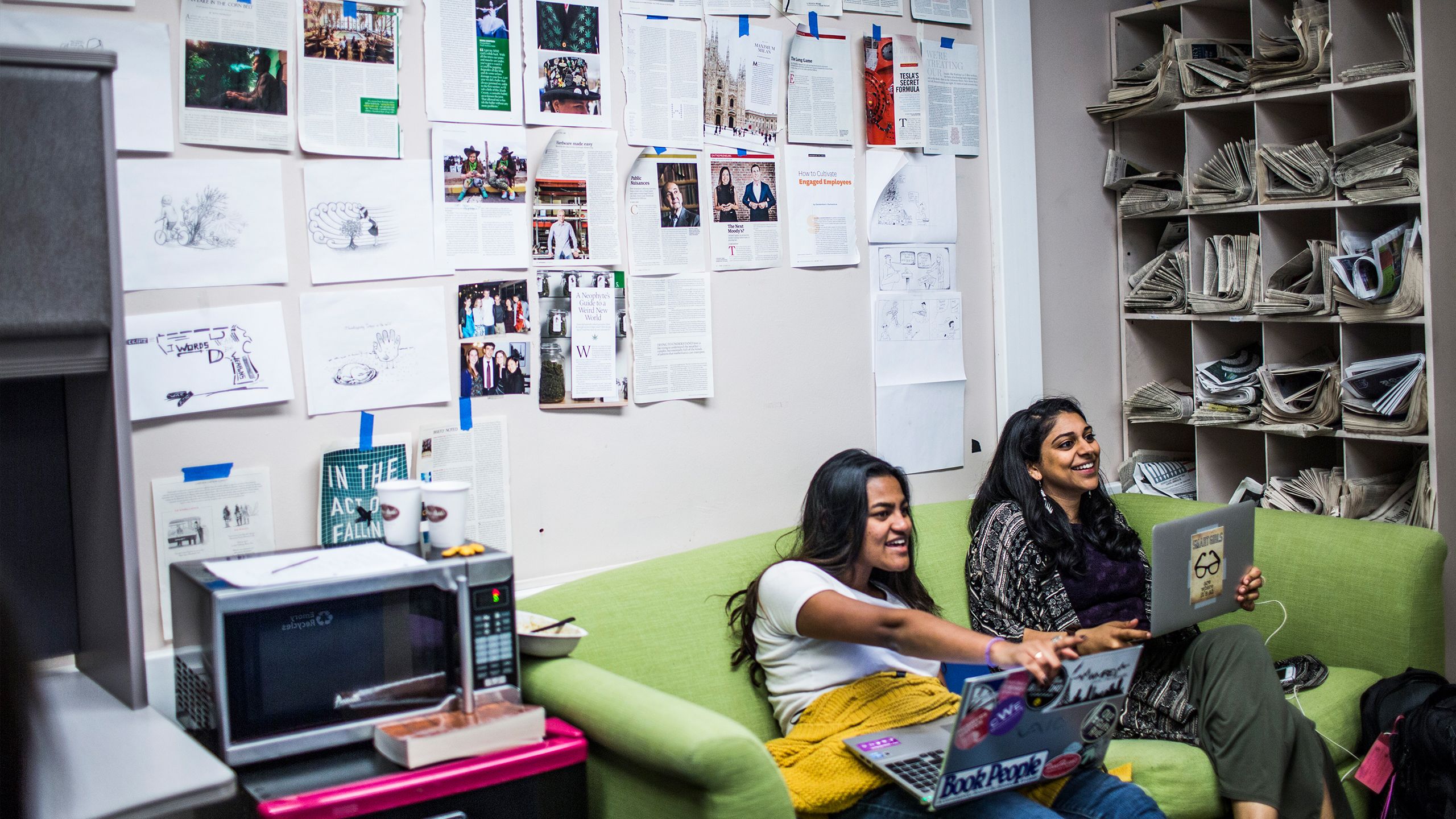 Two students with laptops sitting on couch in The Emory Wheel office