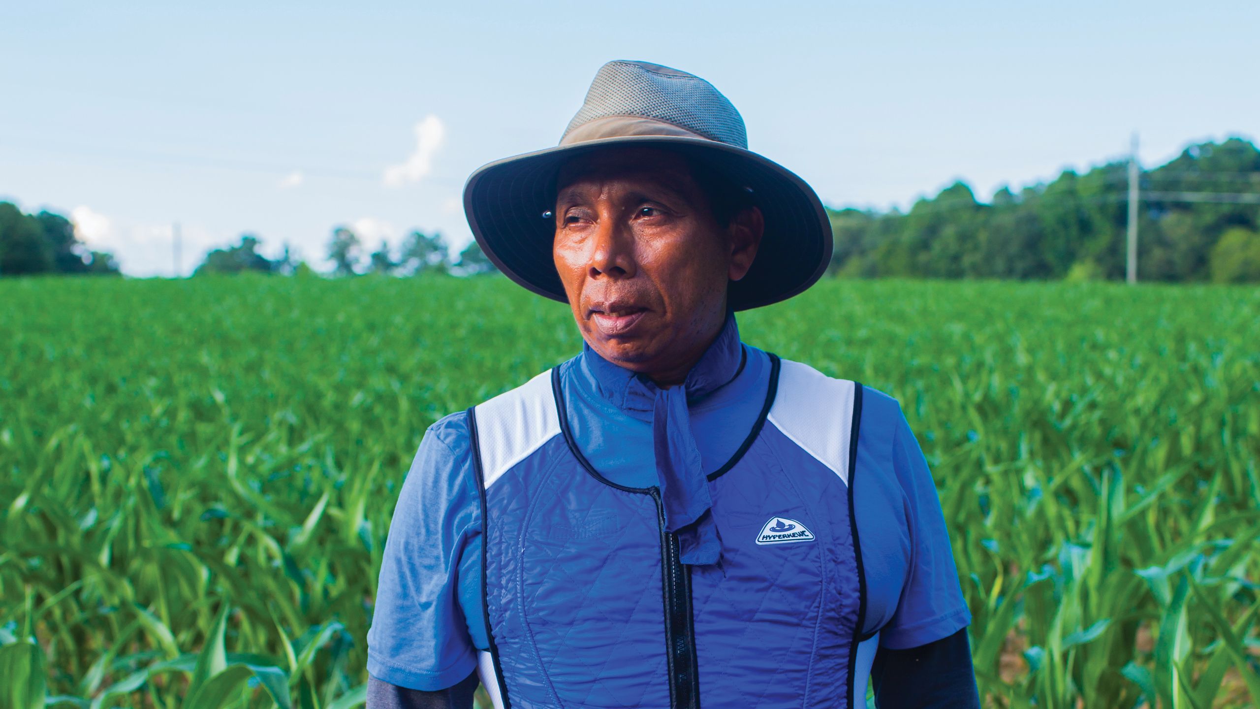 A portrait of the farm worker wearing the temperature monitoring vest in a corn field.