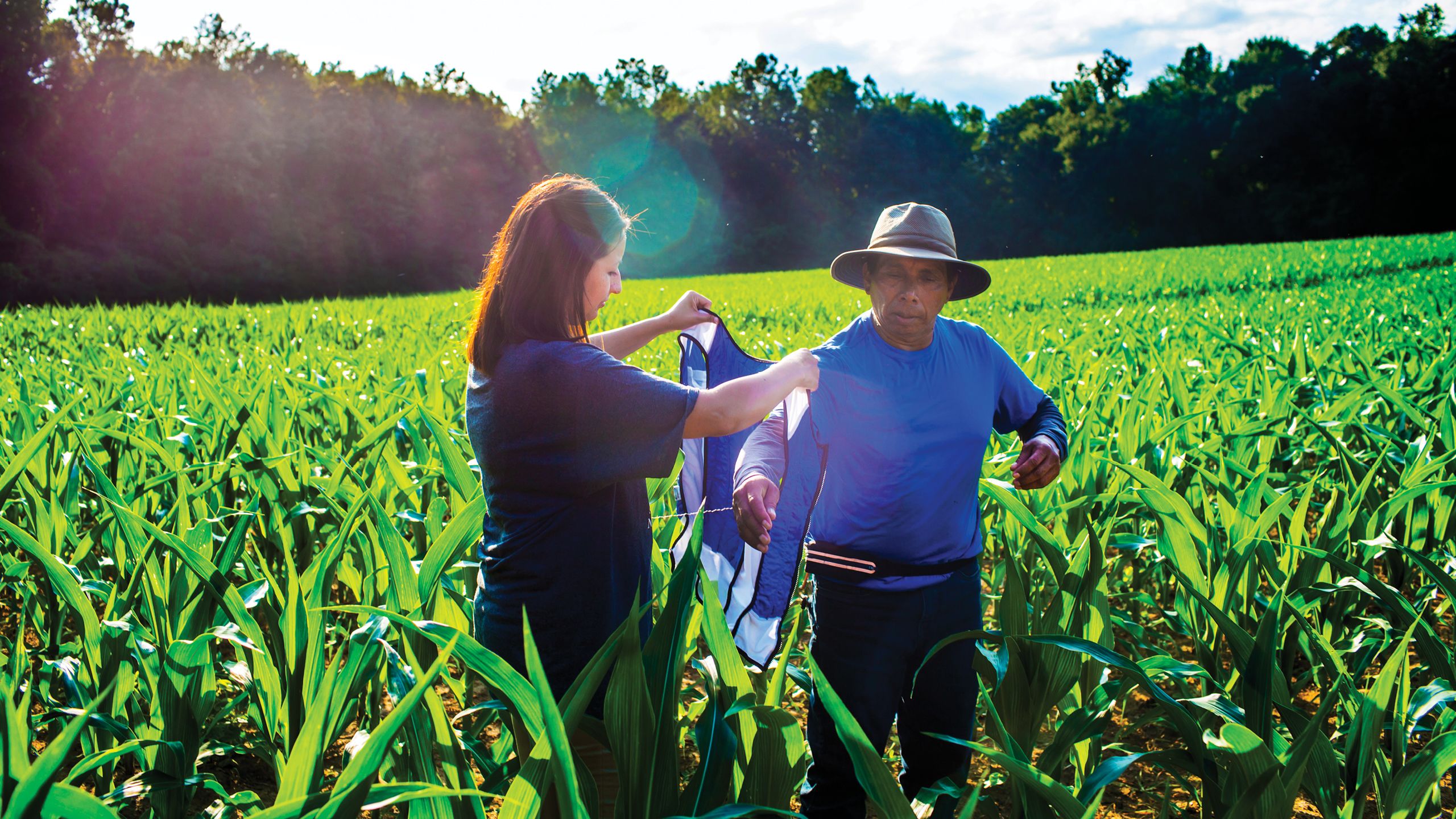A photo of Roxana Chicas placing a vest on a farm worker.