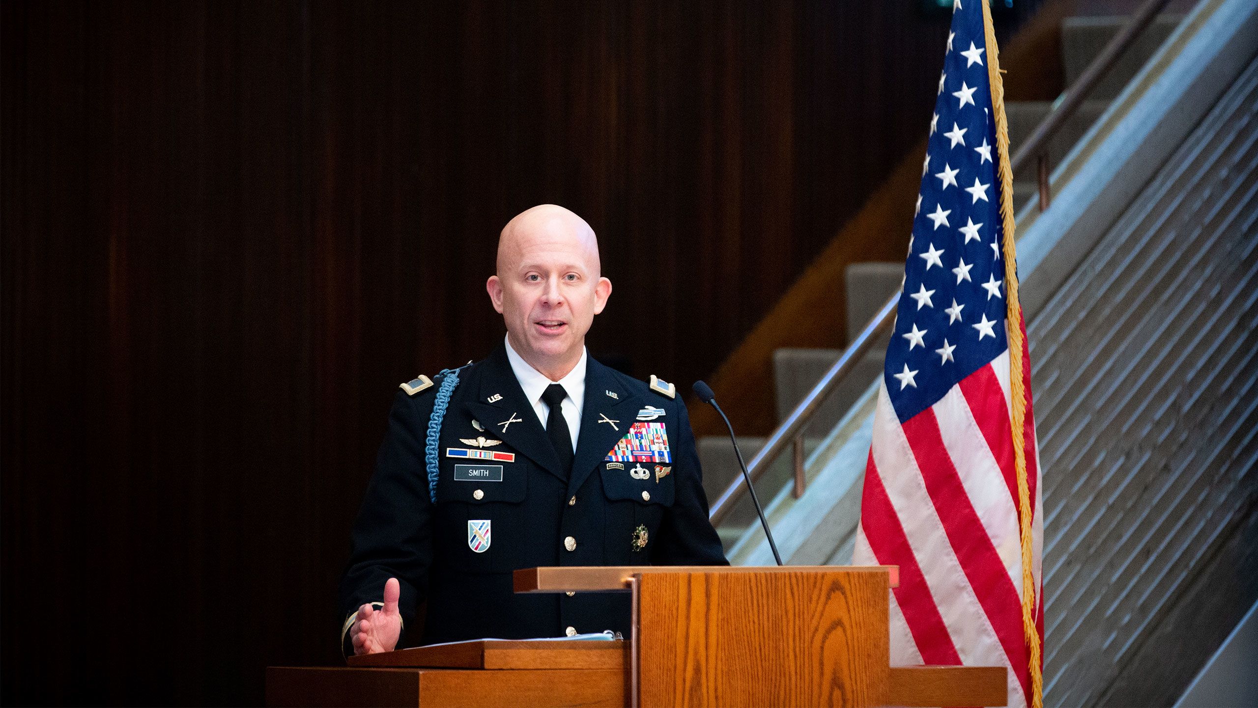 Col. Matt Smith stands in uniform by an American flag at the podium in Cannon Chapel.