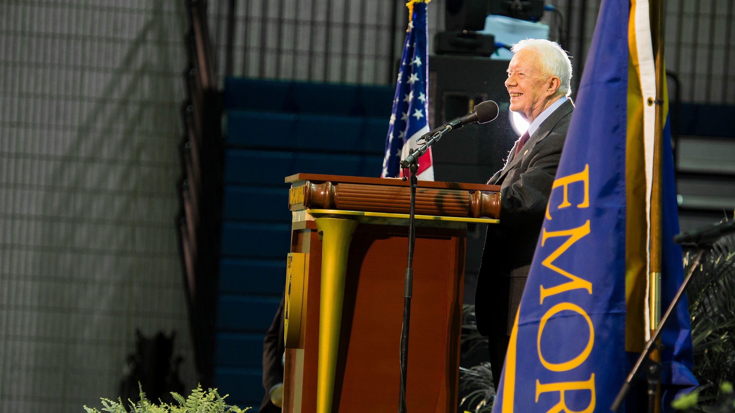 President Carter speaks at a podium with an Emory flag by the side