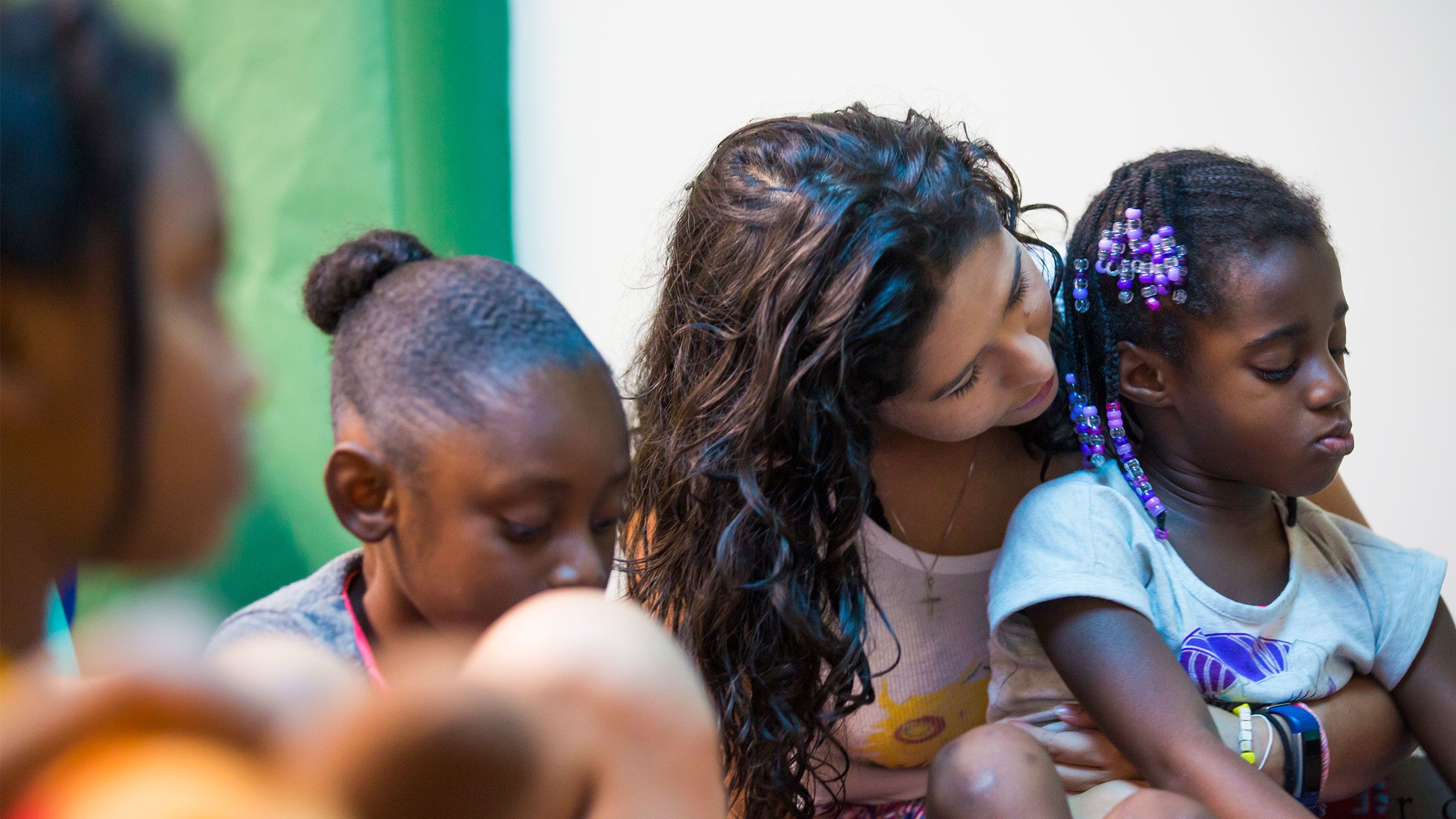 An Emory student holds a child on her lap while sitting in a circle with other children