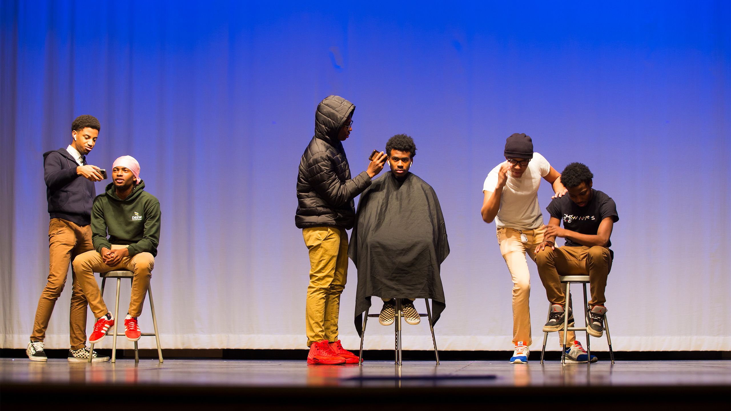 Male students act out a conversation in a barber shop