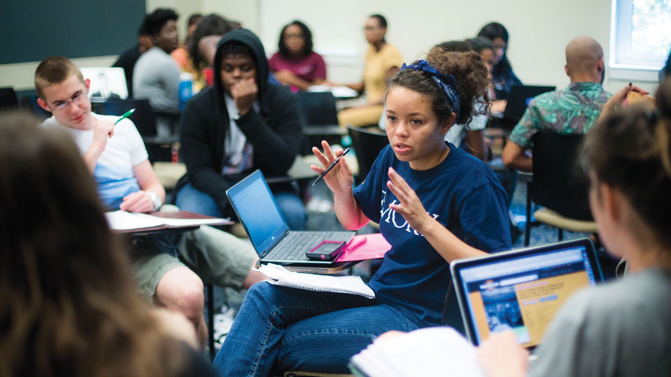 Students with laptops discuss ideas in a classroom