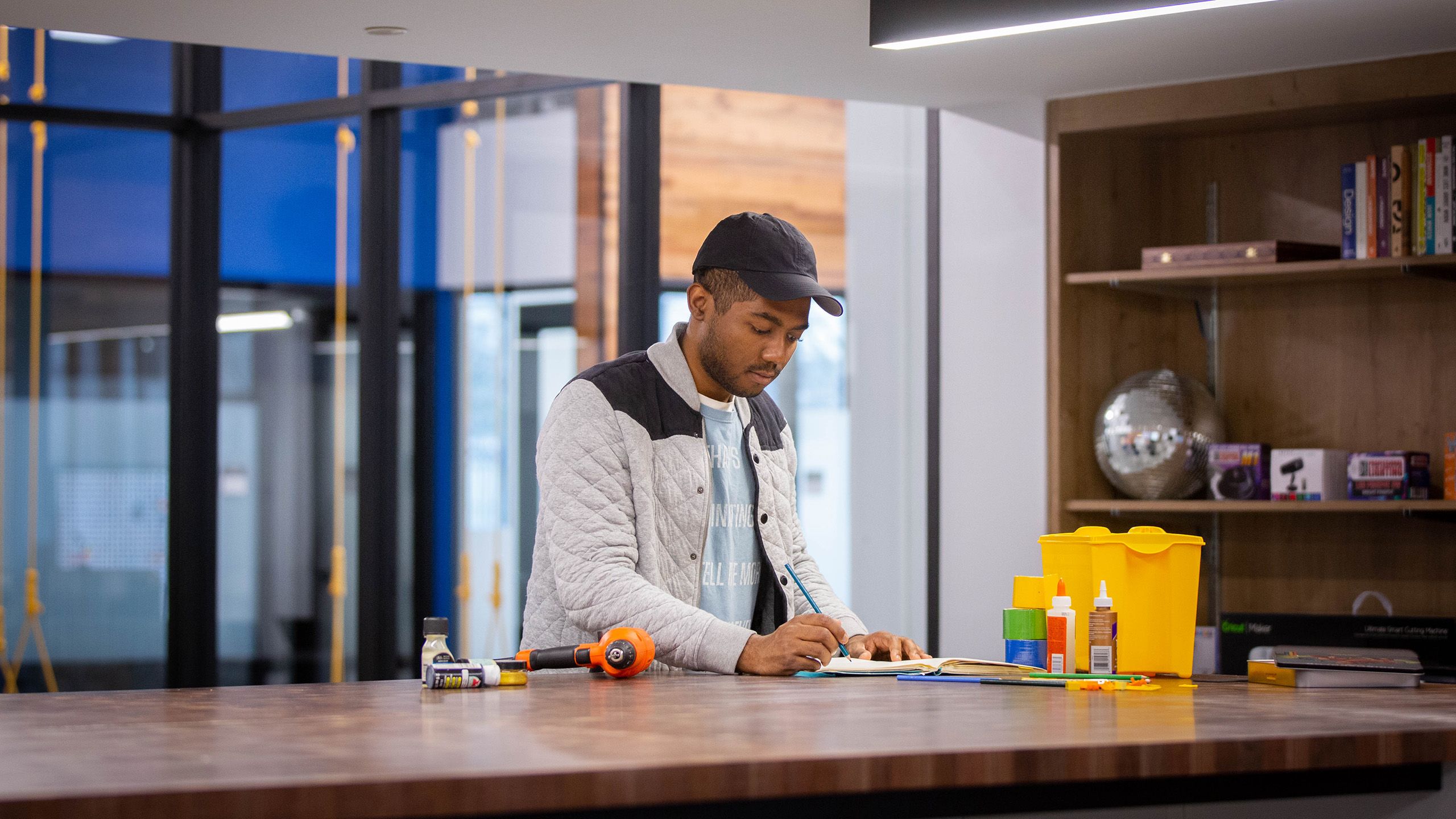 A student drawing on a pad in the makerspace area