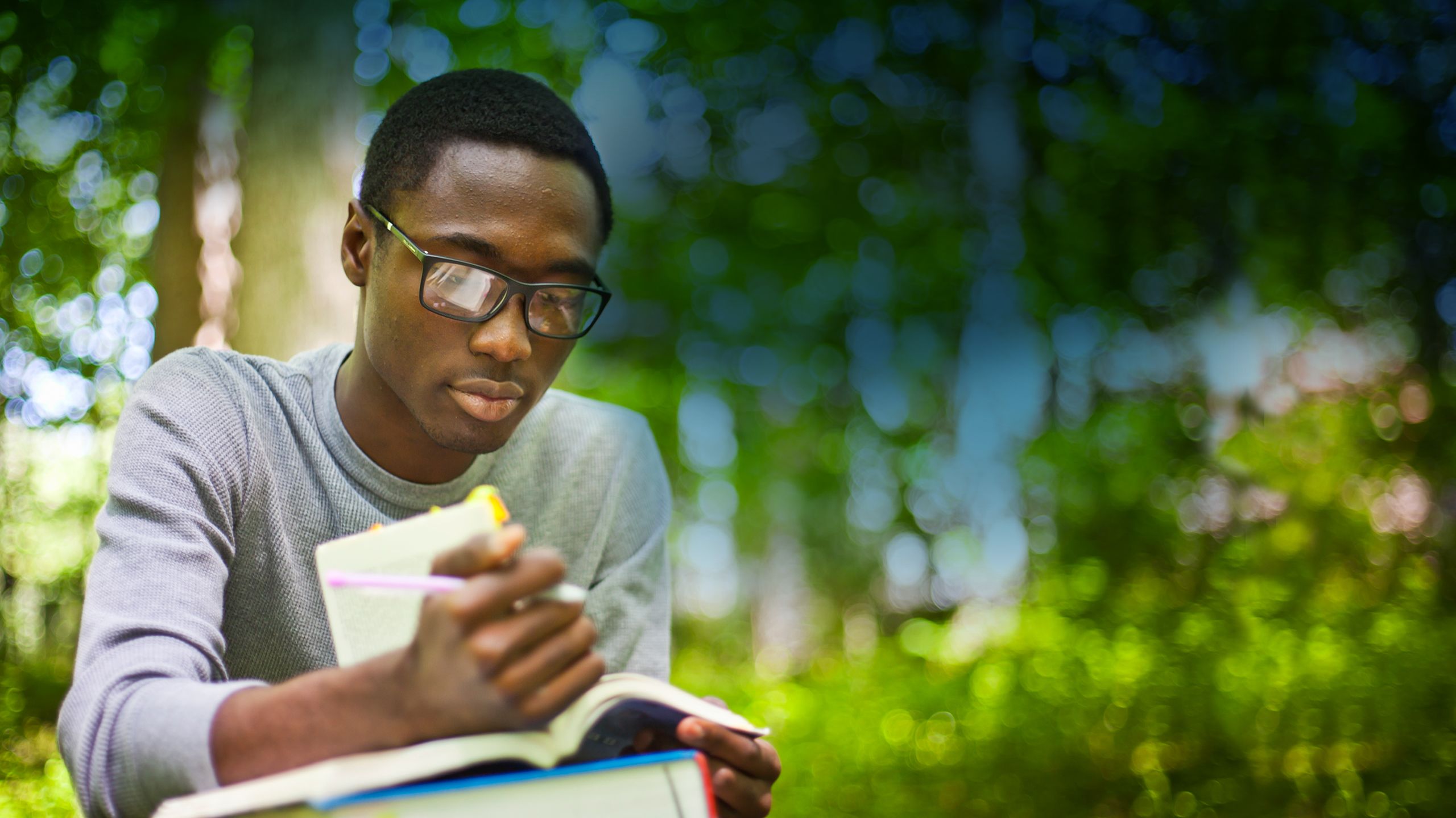 Emory student reading book trees in background