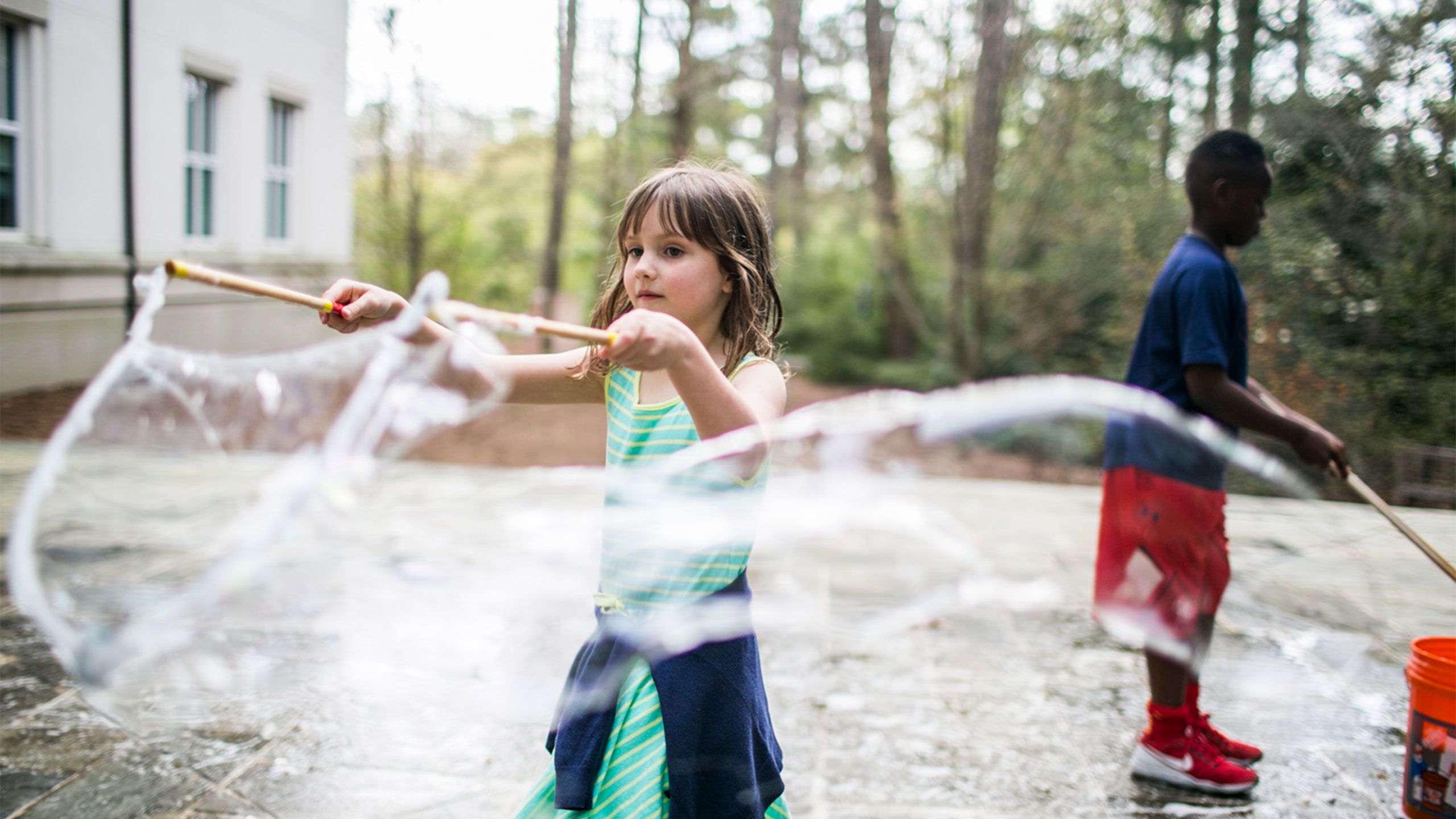 Two children create huge bubbles outside on the Emory campus.