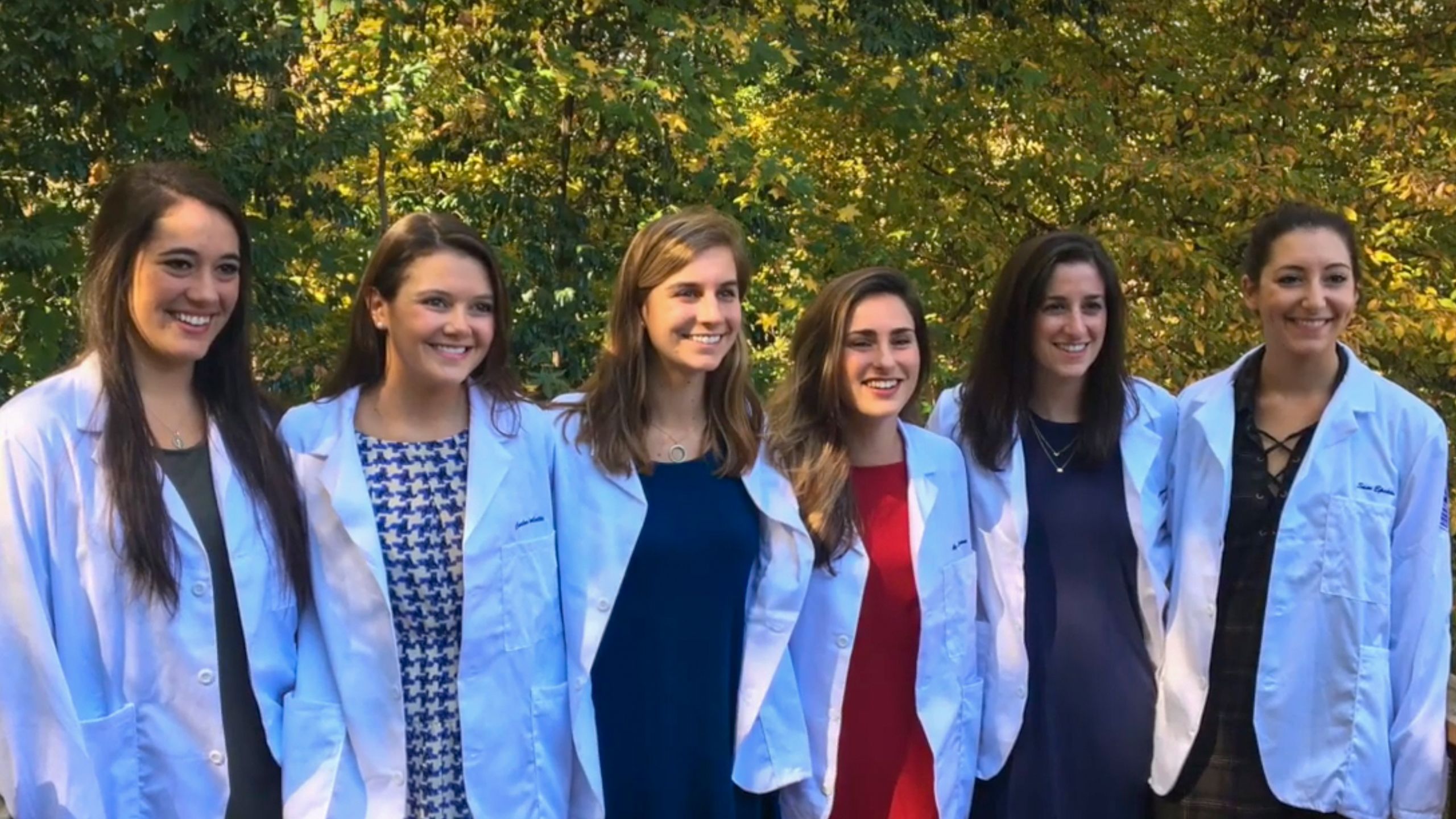 A group shot of six medical students in white coats. 
