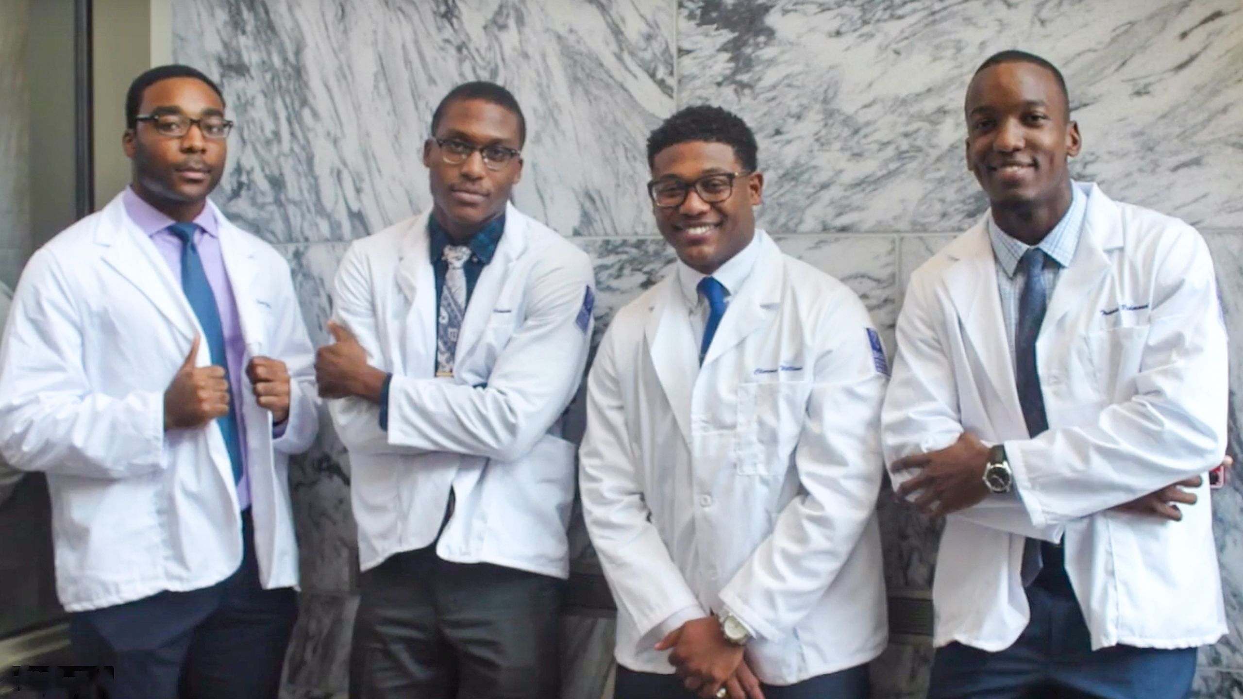 A group of four medical students in white coats.