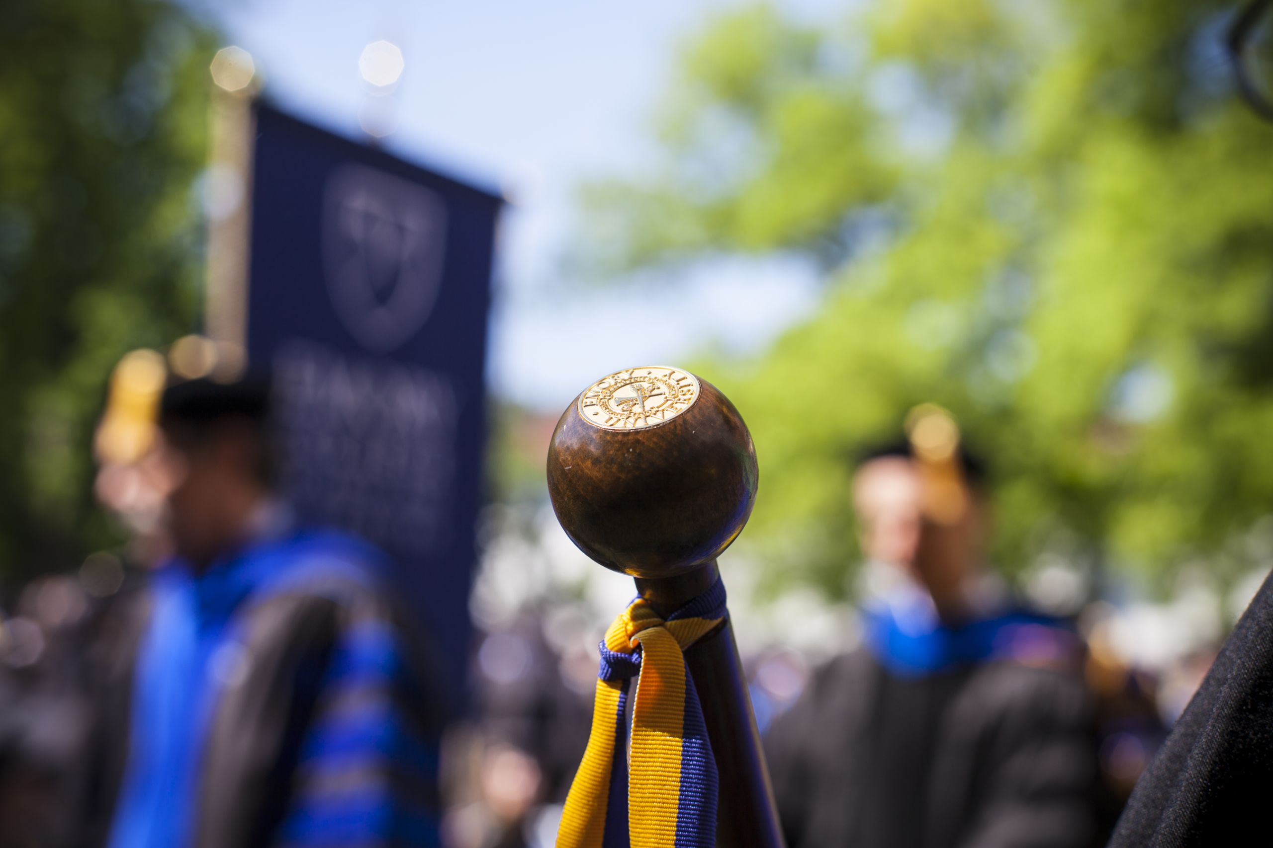 A background photo of students in caps and gowns at commencement
