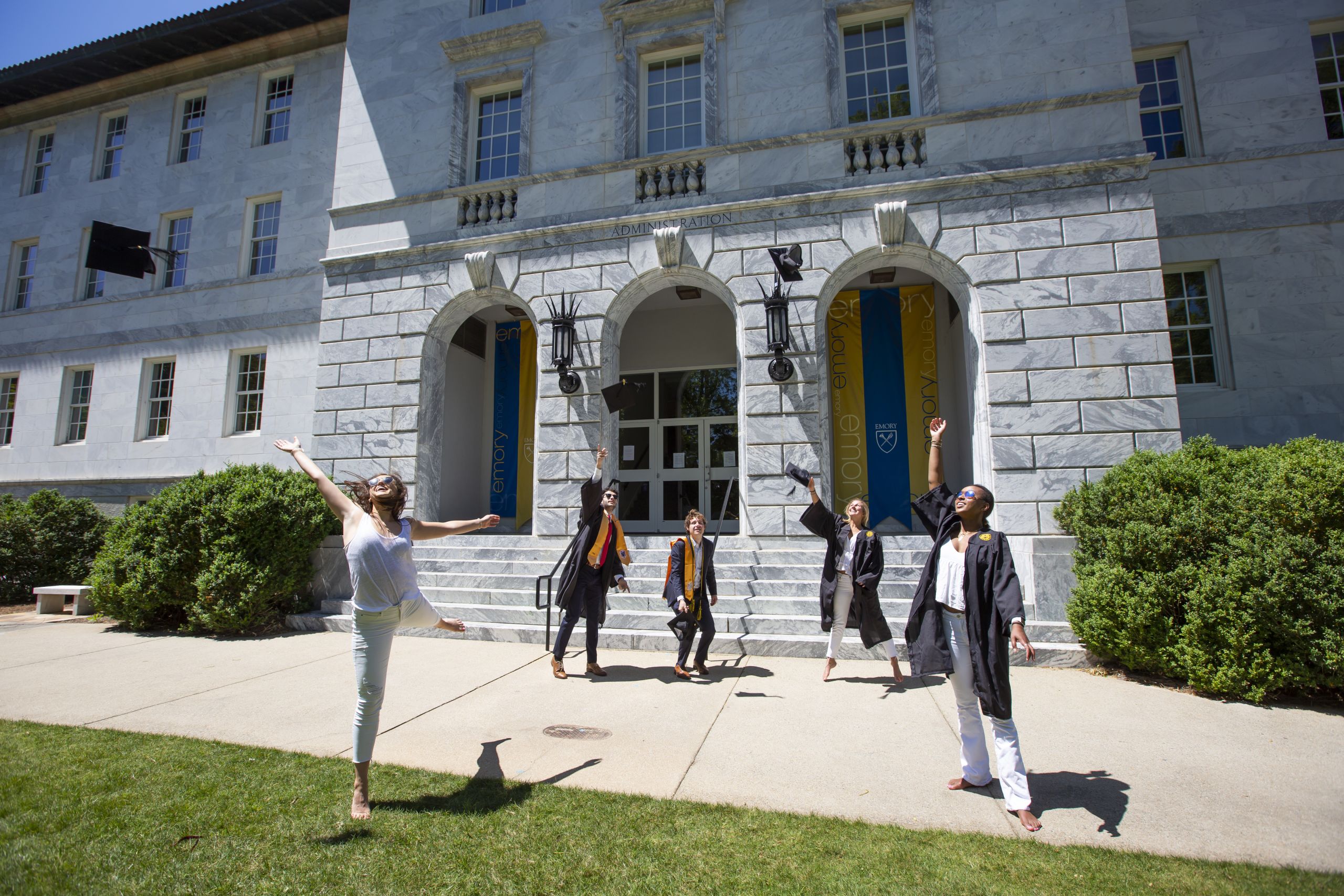Several students standing spread out toss their graduation caps in the air