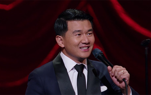 Ronny Chieng stands on stage with a microphone