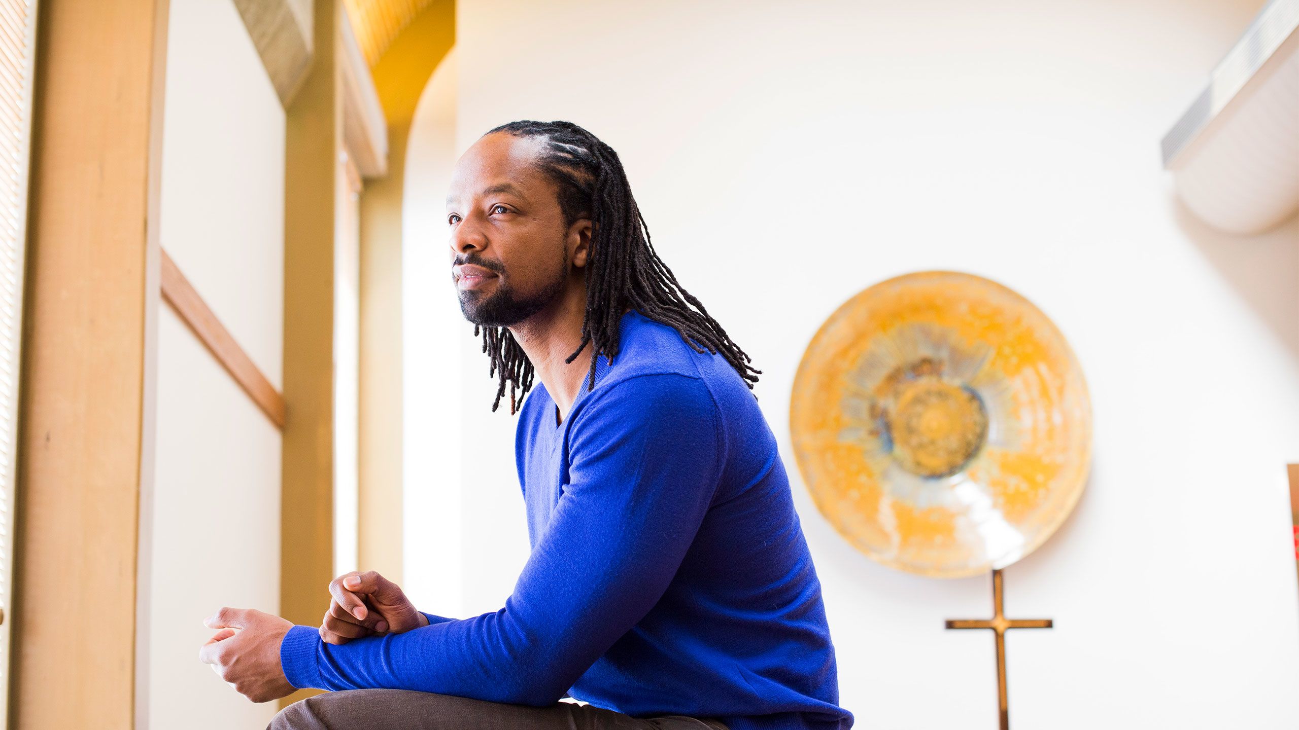 Poet and professor Jericho Brown appears in profile wearing a blue sweater