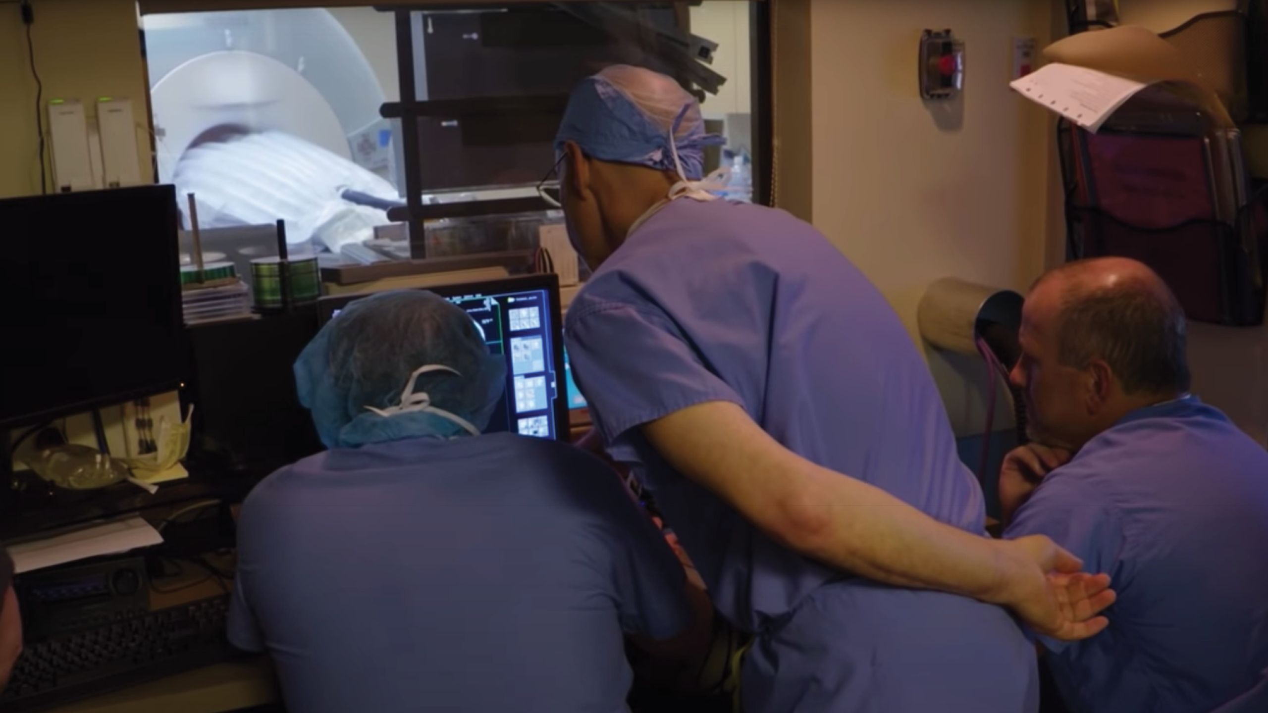 Doctors from the back bent over reviewing a computer screen.