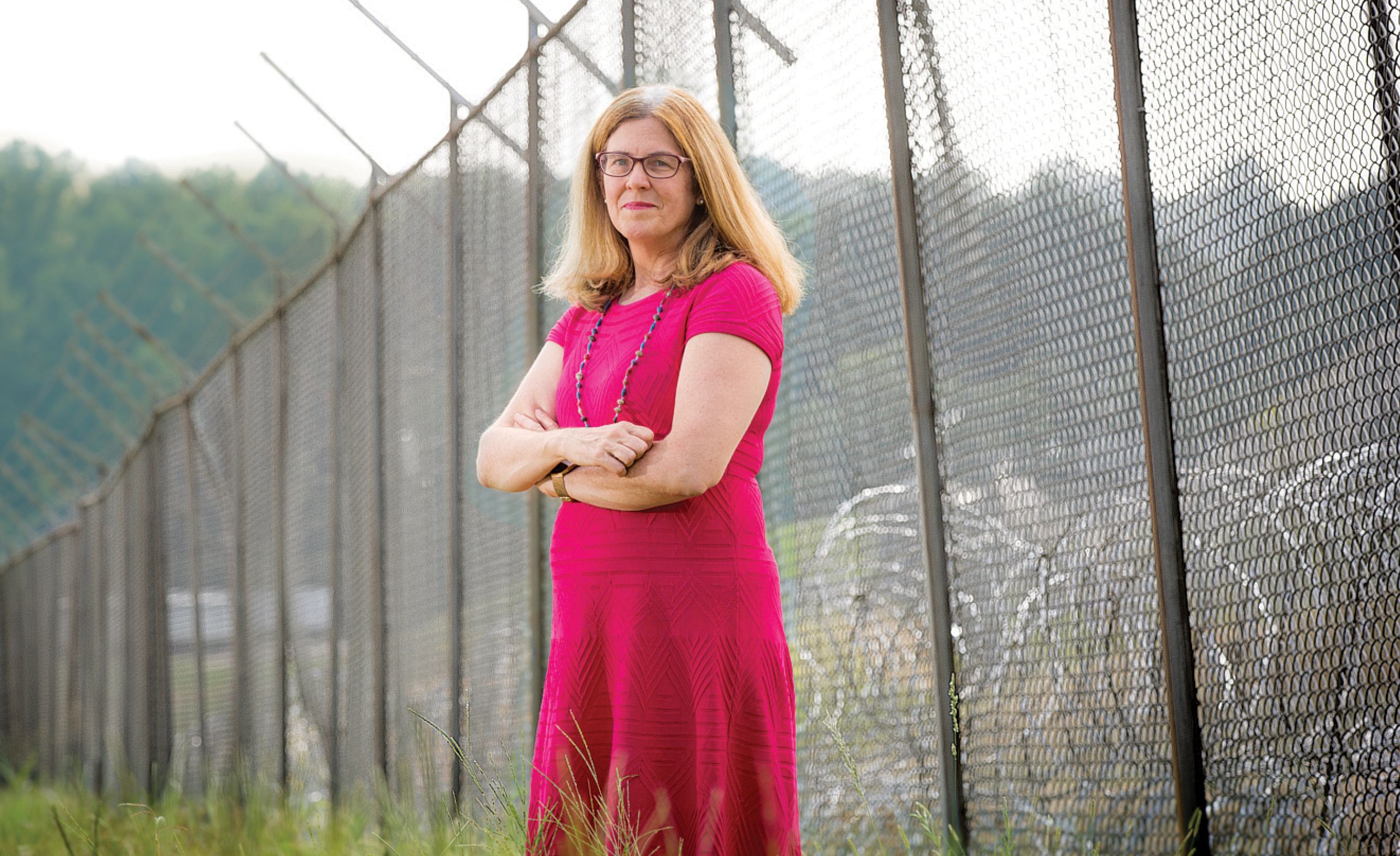 Dr. Anne Spaulding standing in front of a prison's barb-wired fence.
