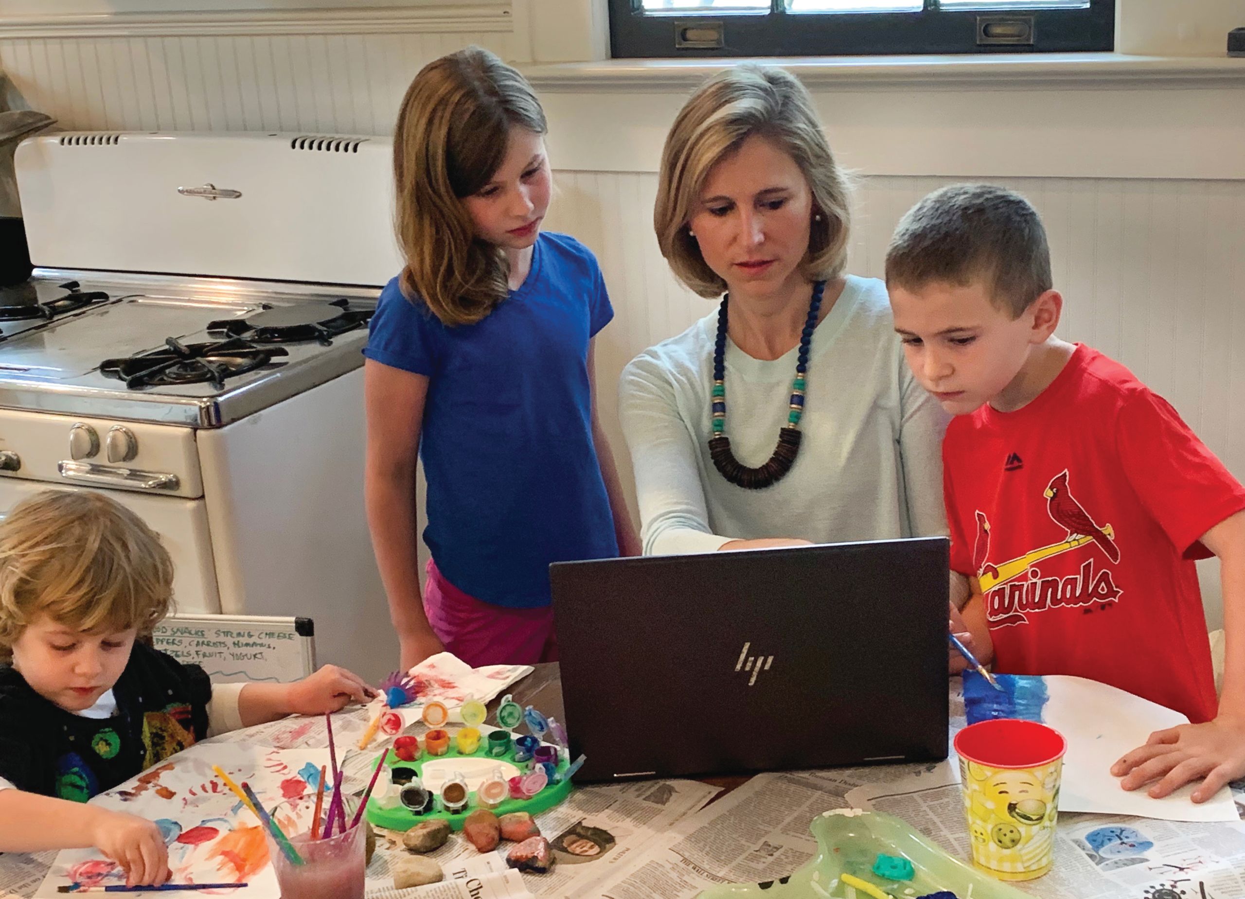 Allison Chamberlain with her children in the kitchen looking at a computer screen and making art.