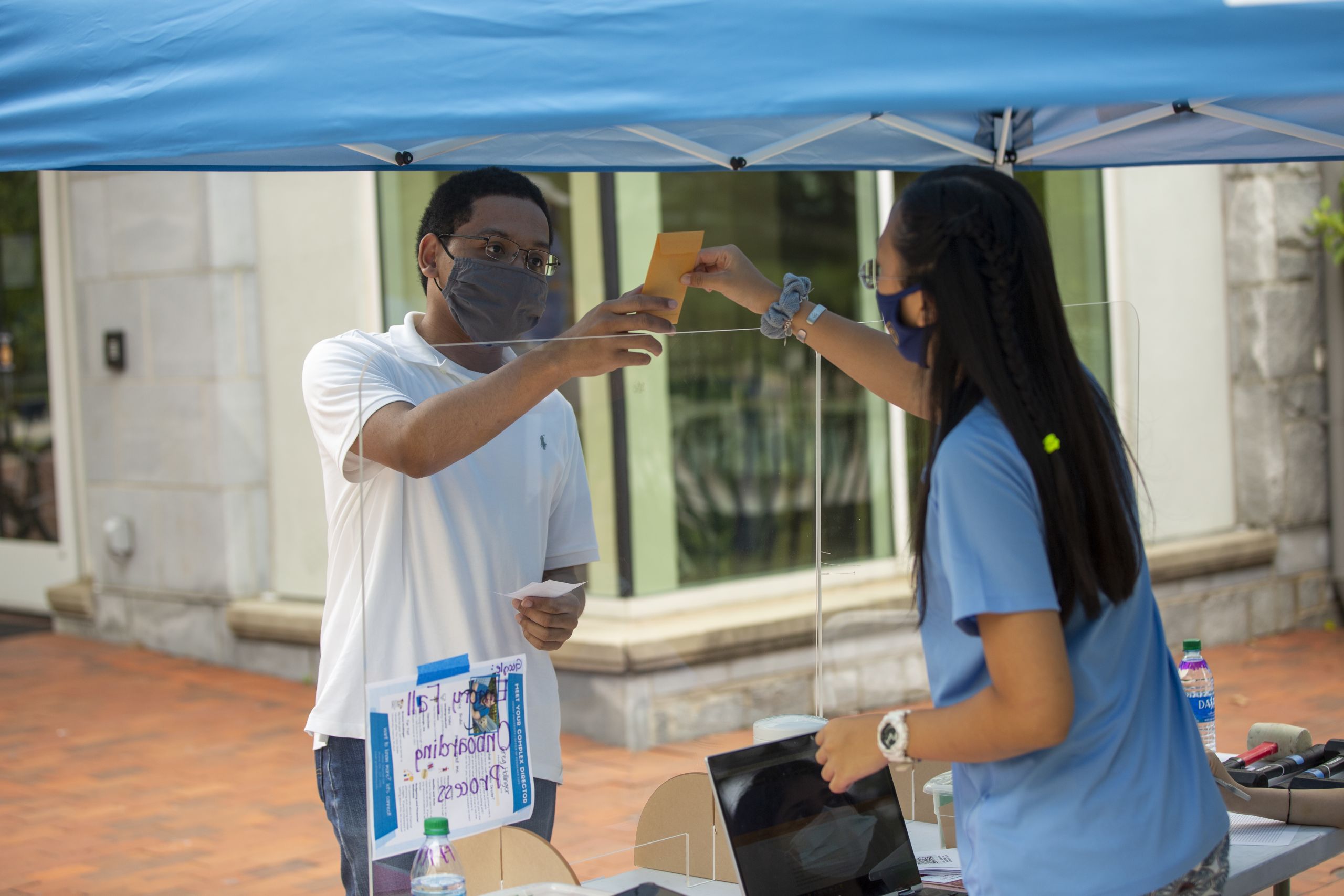 A new student wearing a face covering checks in at a tent