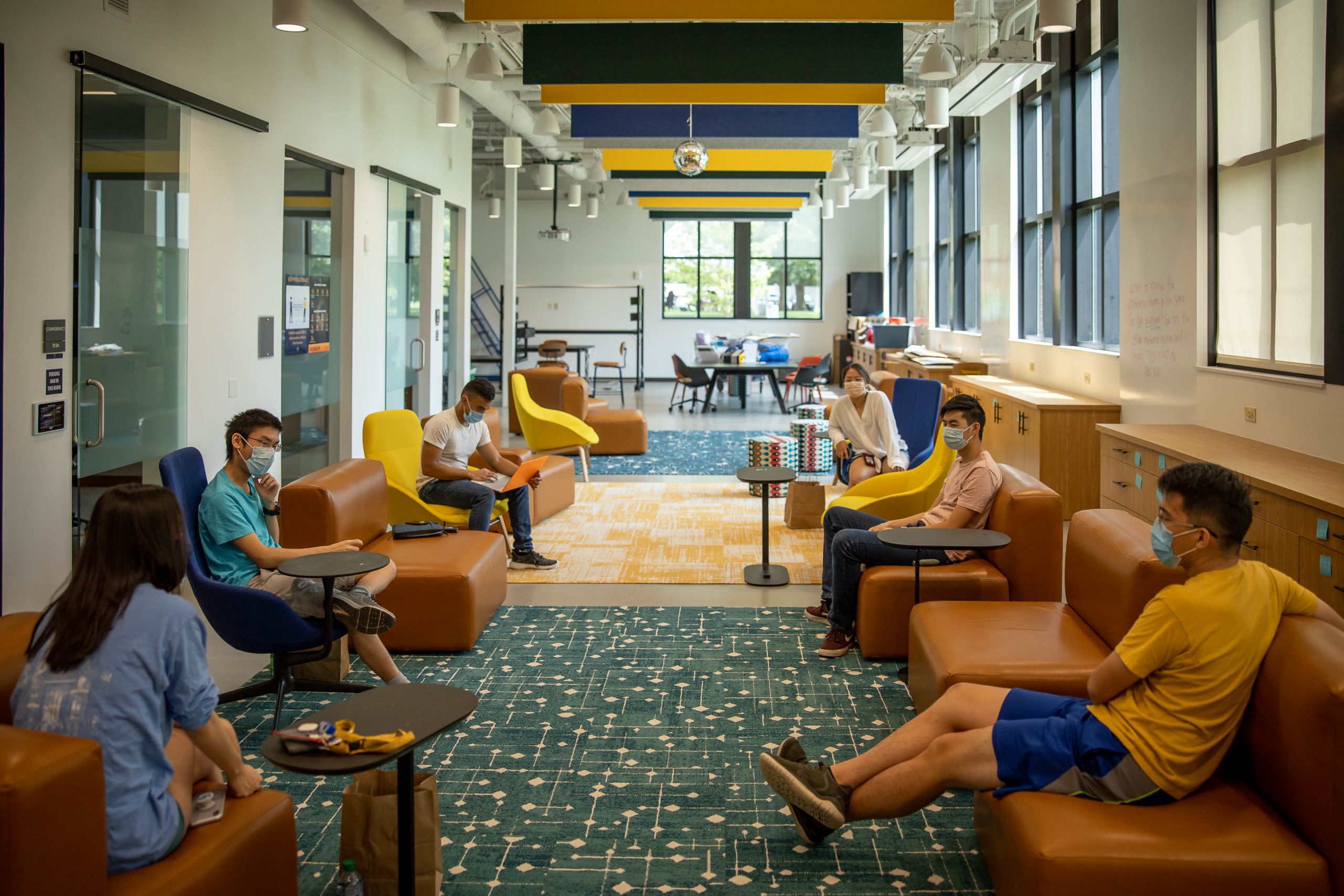 Students wearing face masks visit in the Oxford Student Center, sitting at appropriate distances